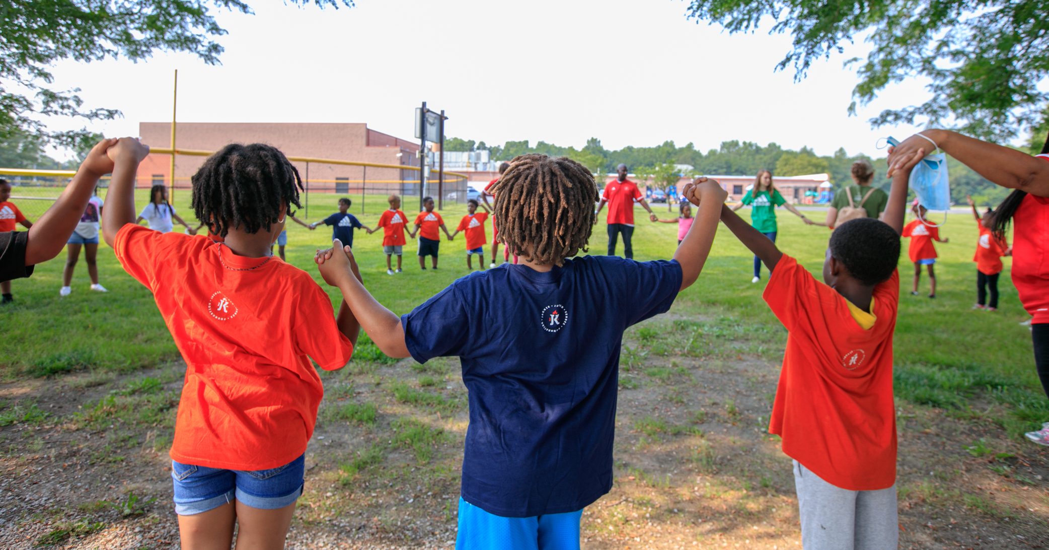 Kids stand in a circle outside holding hands