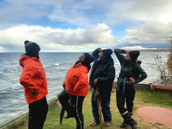 A group of people laugh while standing next to the ocean