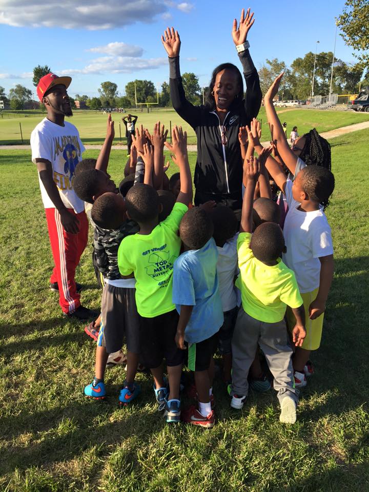 Jackie Joyner-Kersee stands surrounded by young athletes