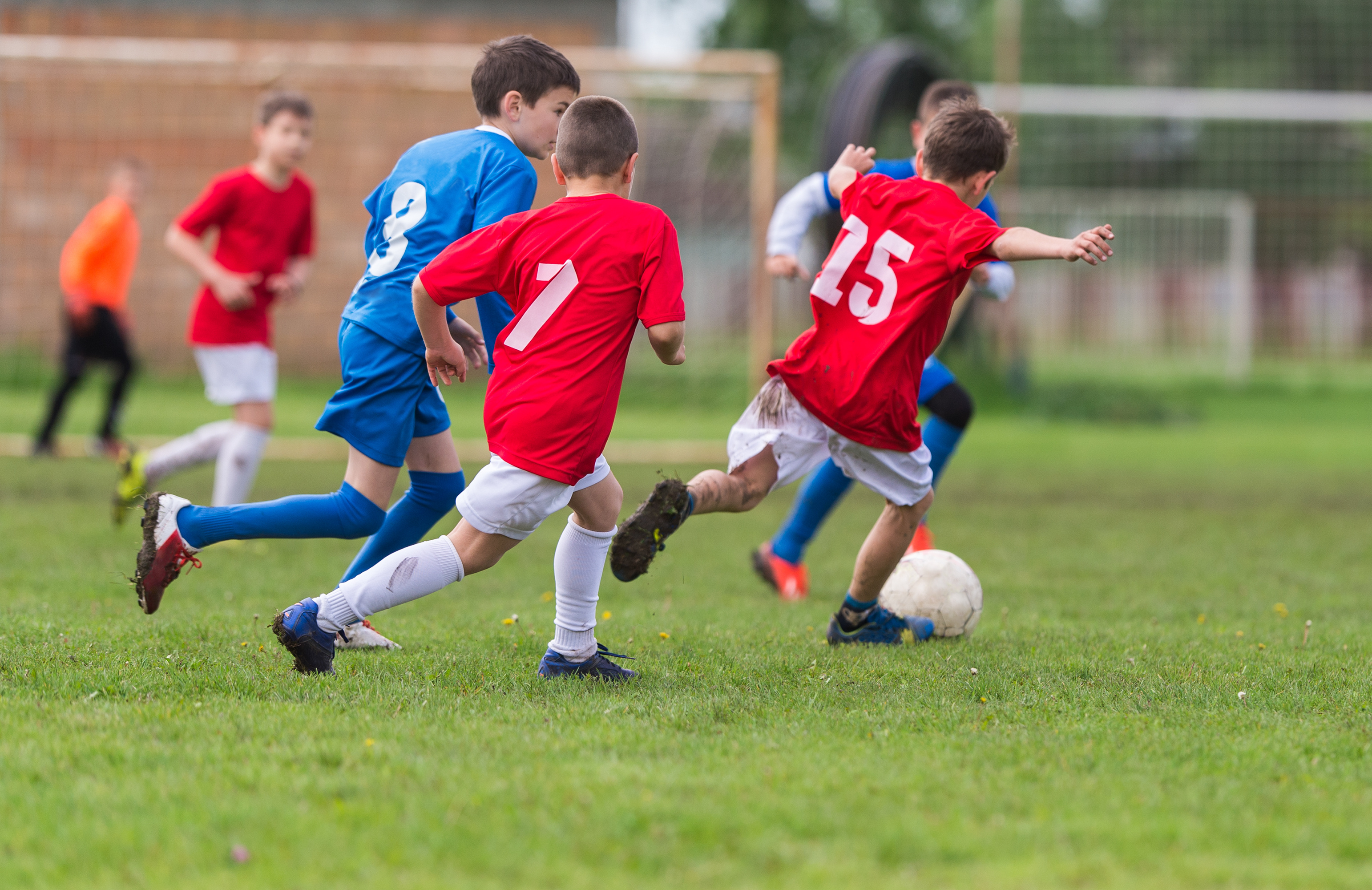 kids run across a field with a soccer ball