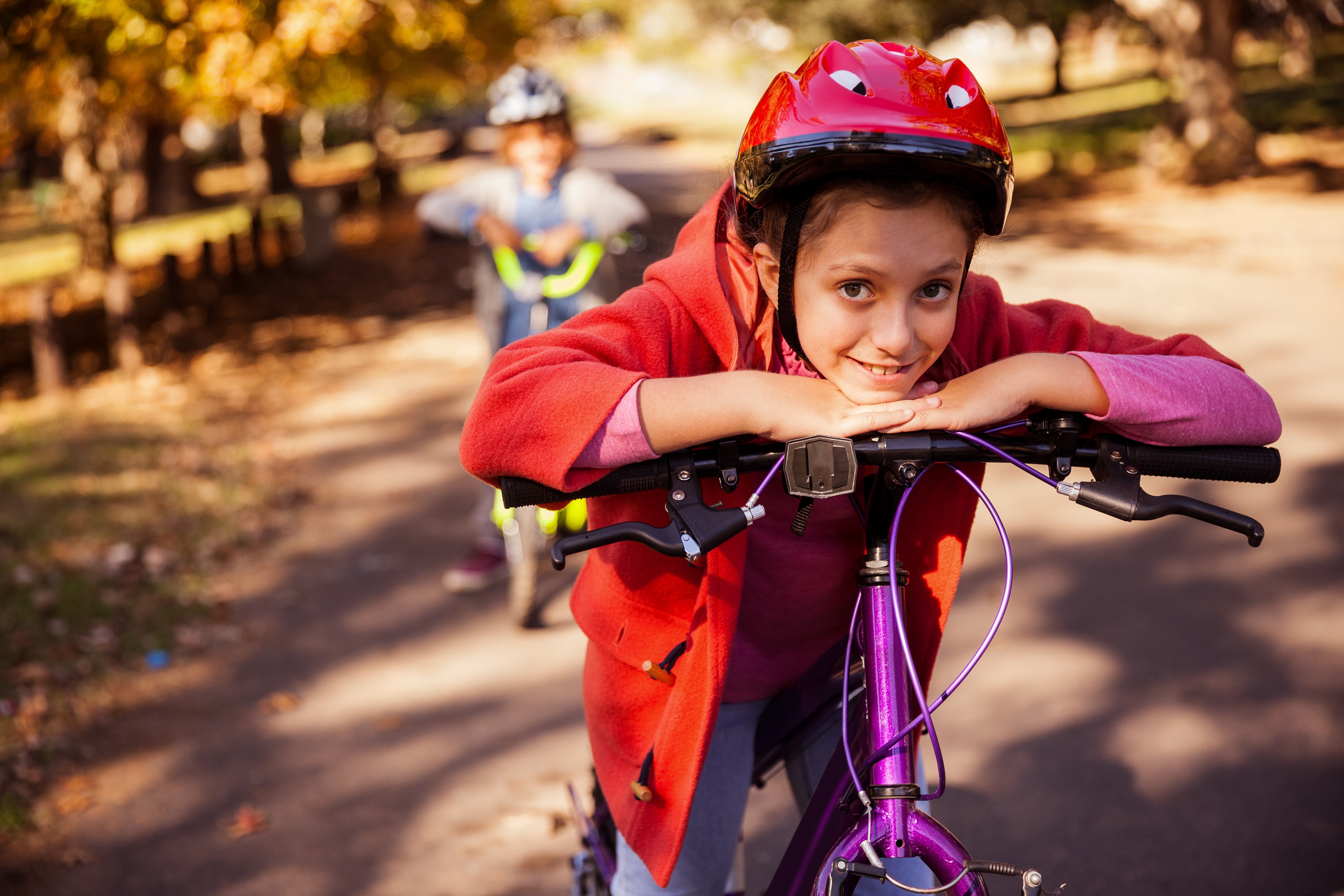 girl in helmet leaning on her bike in a park