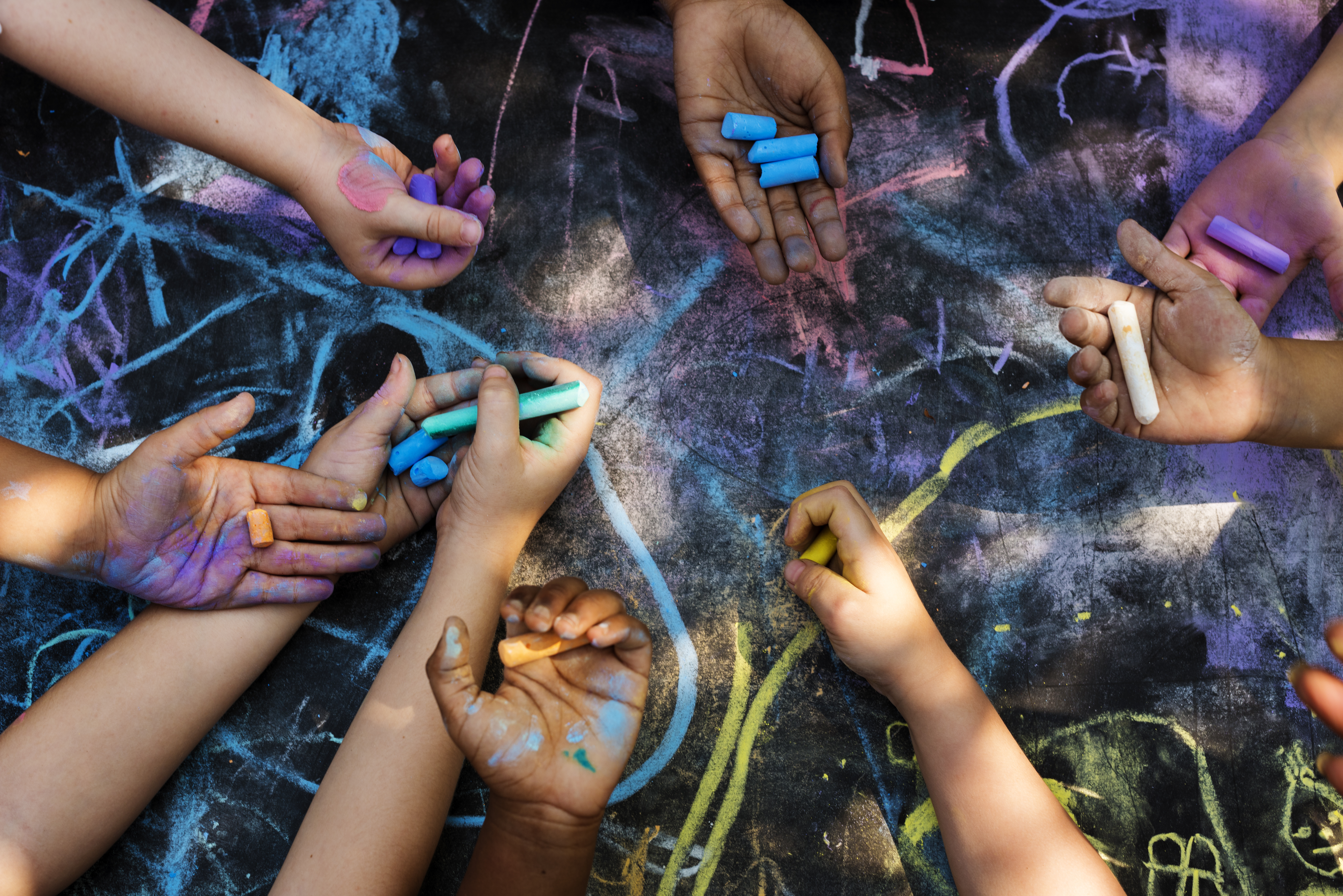 children's hands hold chalk