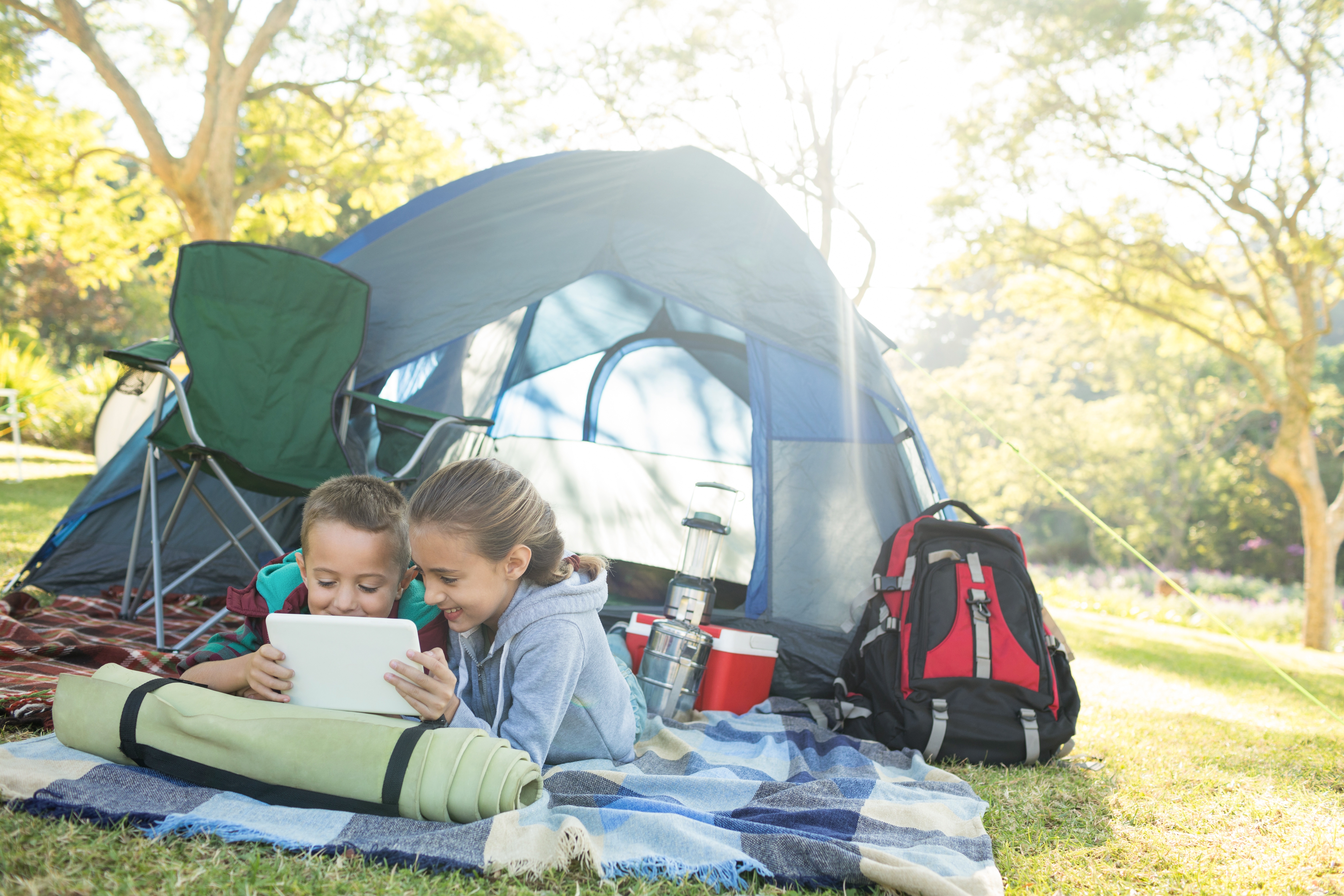 kids on an ipad outside a tent