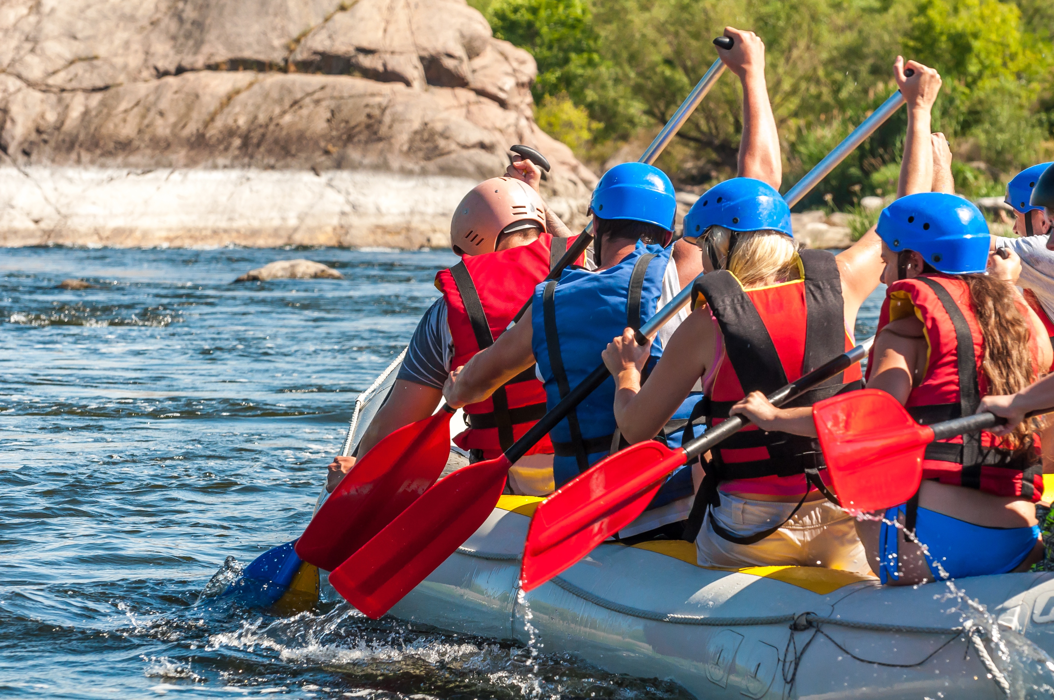 young people paddle a raft on a river