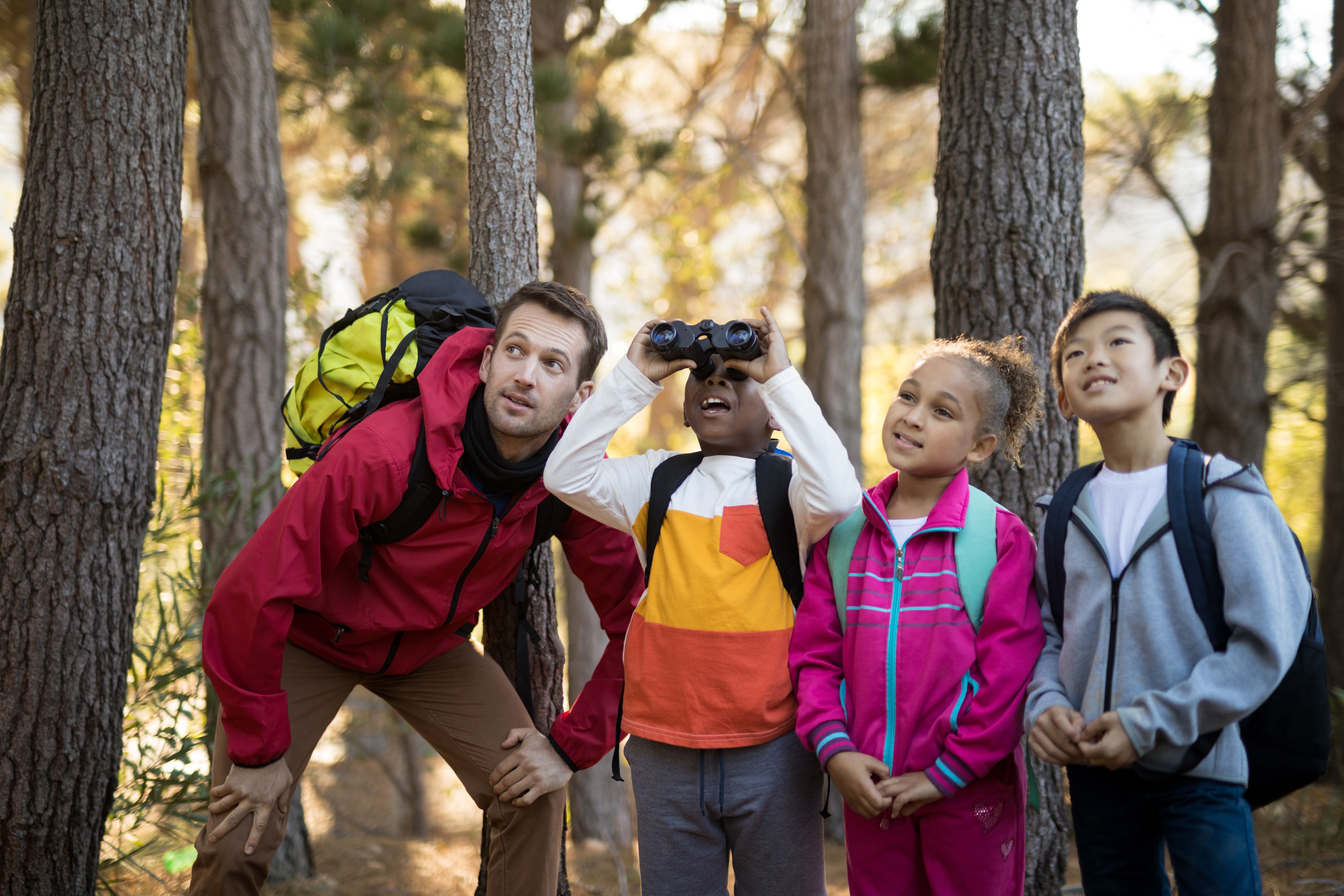 A group of children stand surrounded by trees