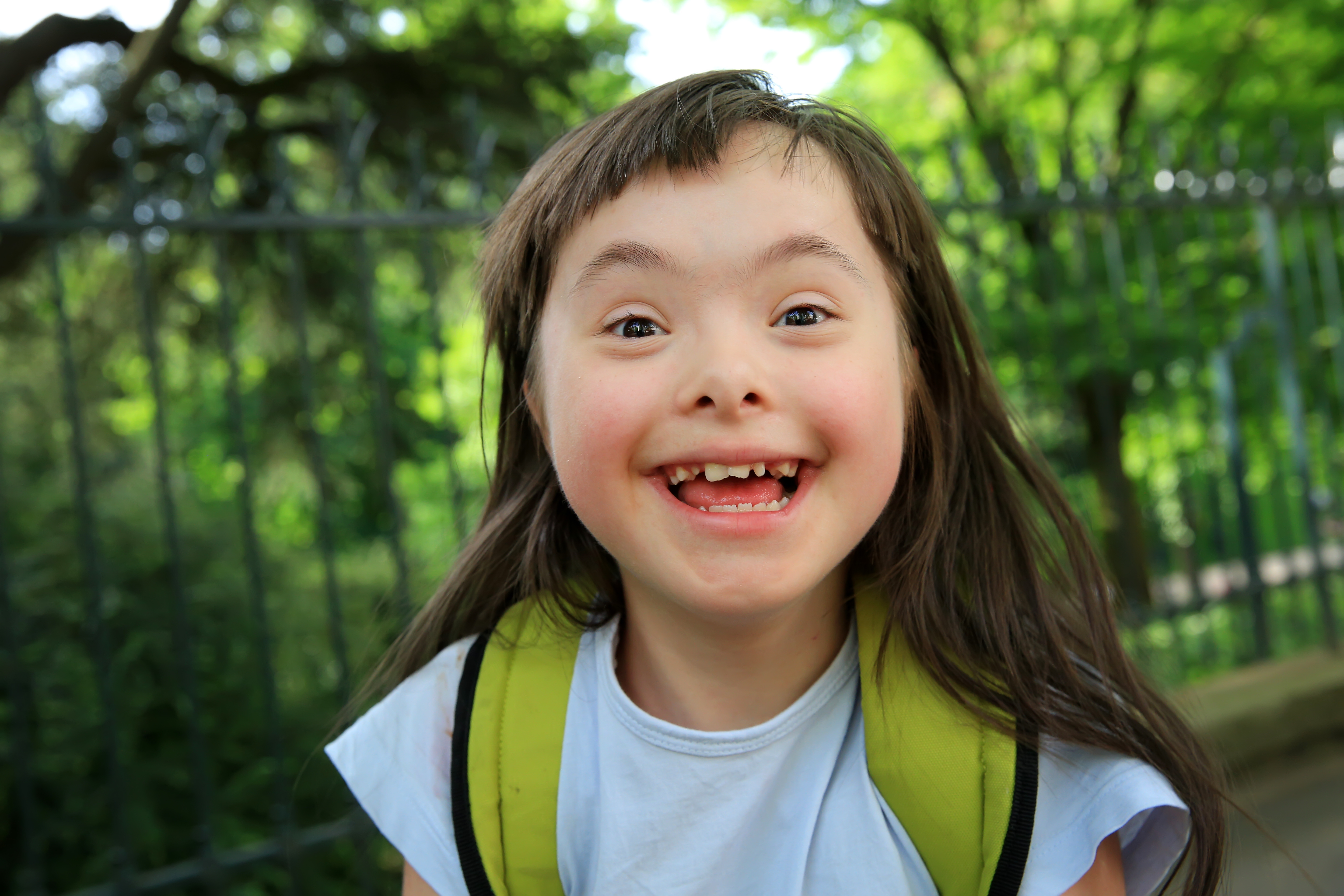 A young person smiles at the camera in the park