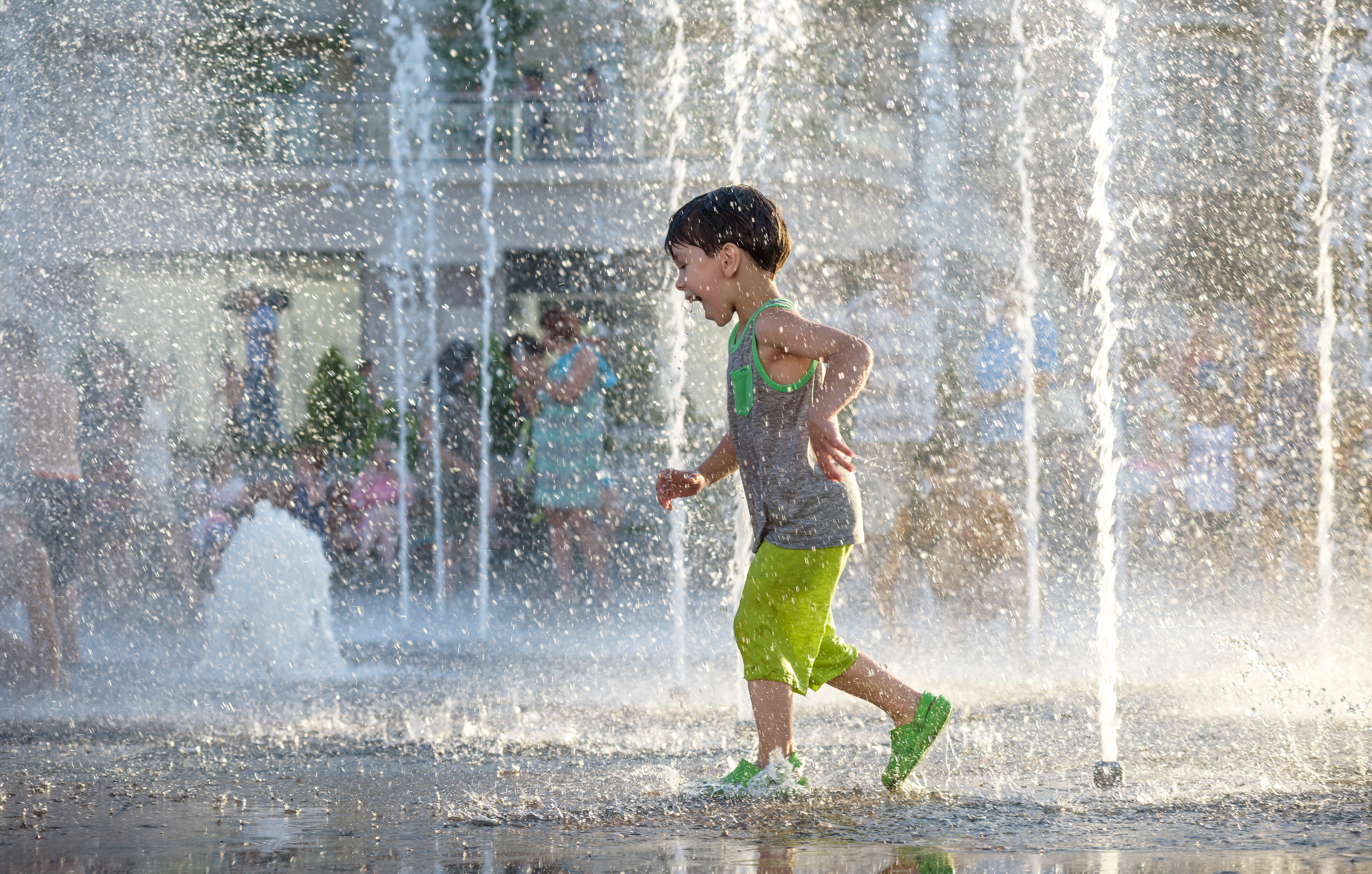 a child runs through a water play feature