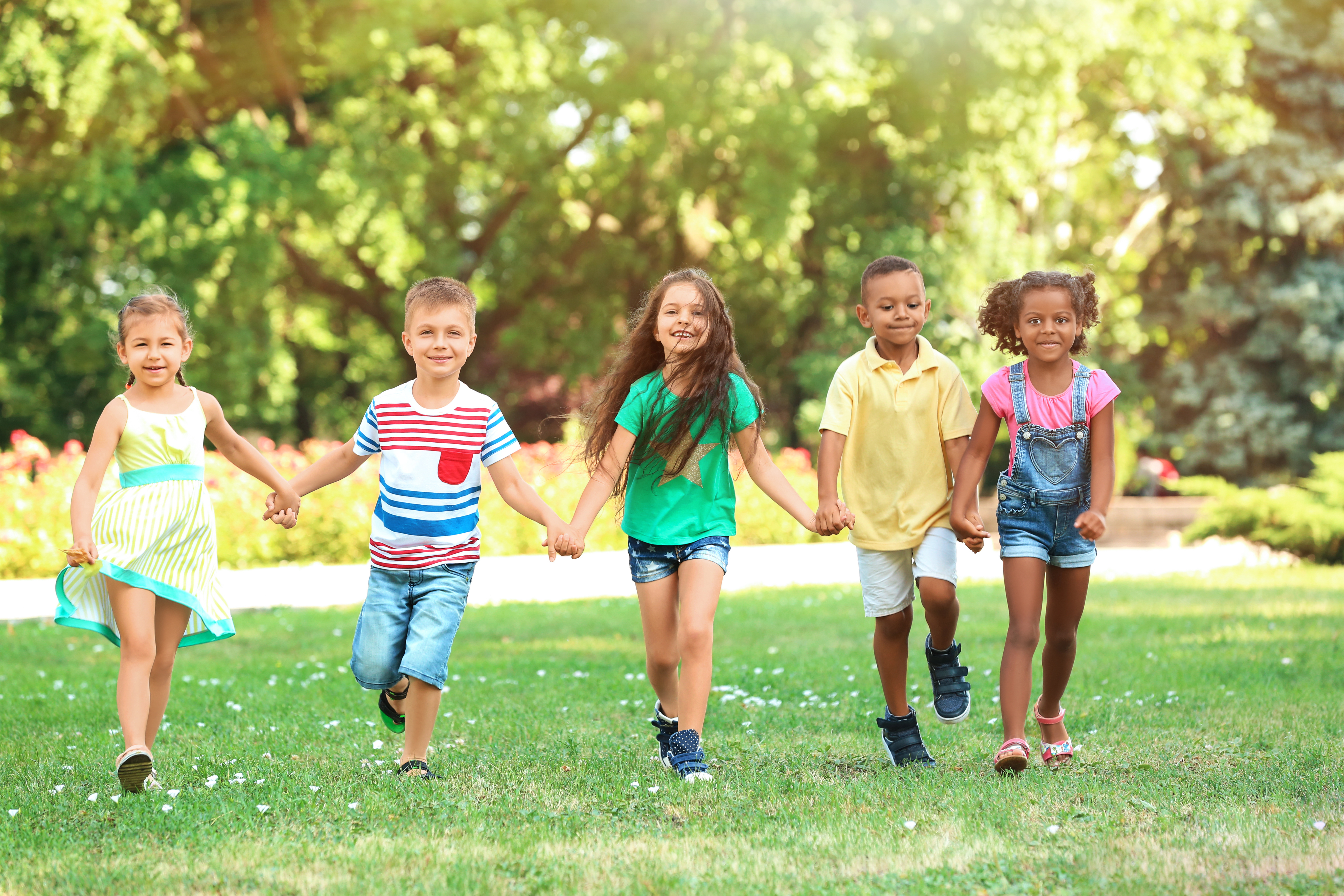 a group of children walk hand in hand through a park