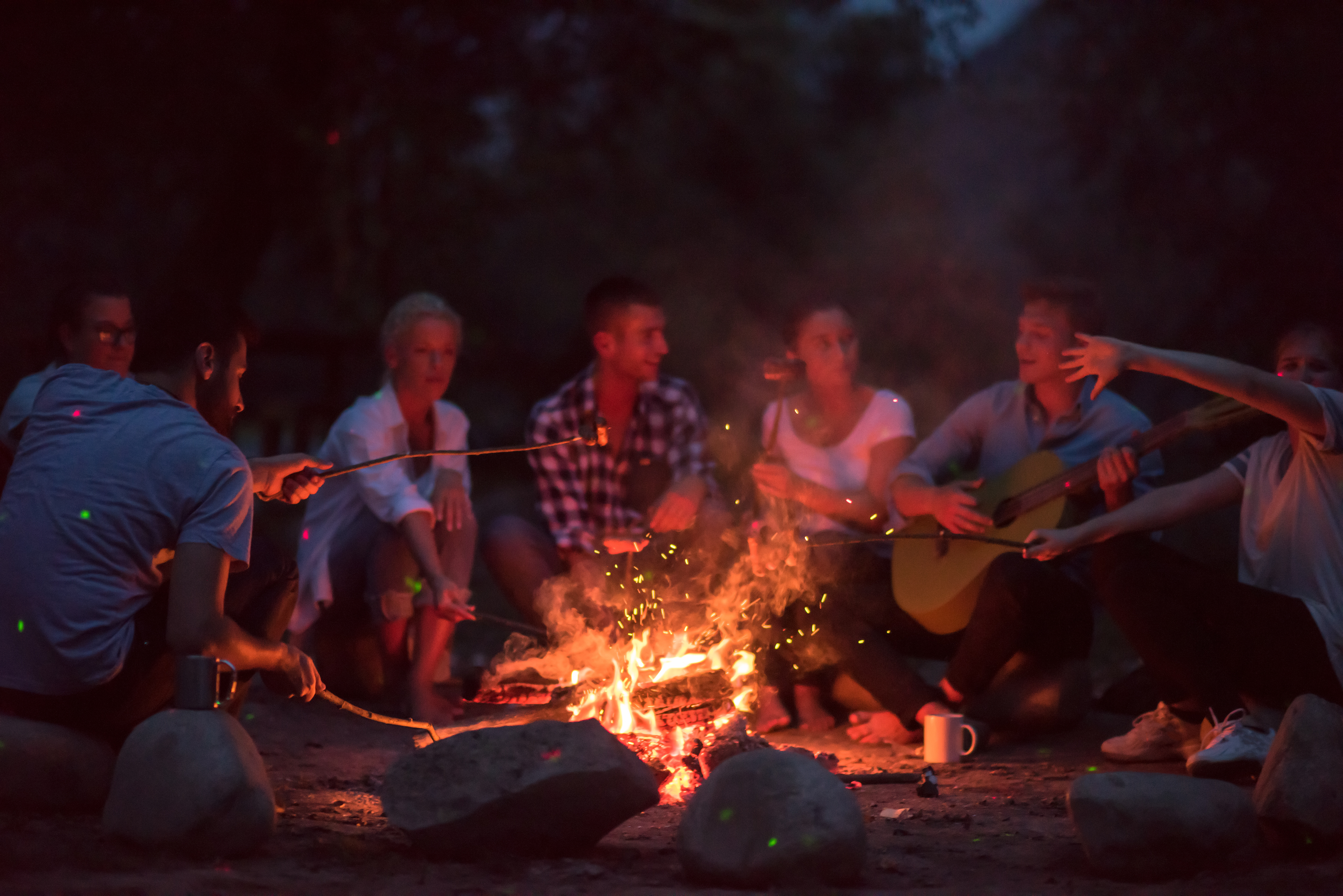 a group of young people sit around a campfire