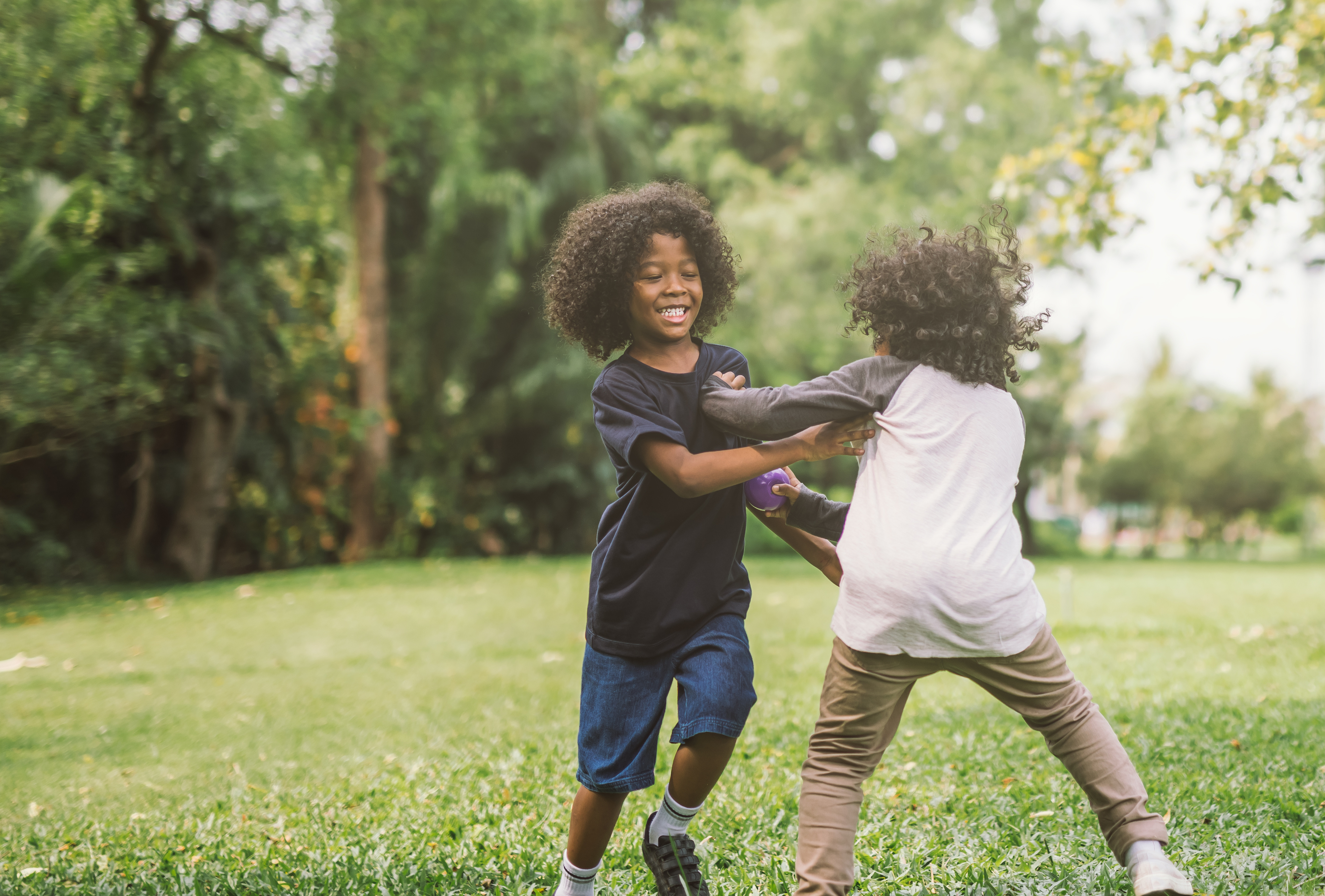 two kids play on a lawn