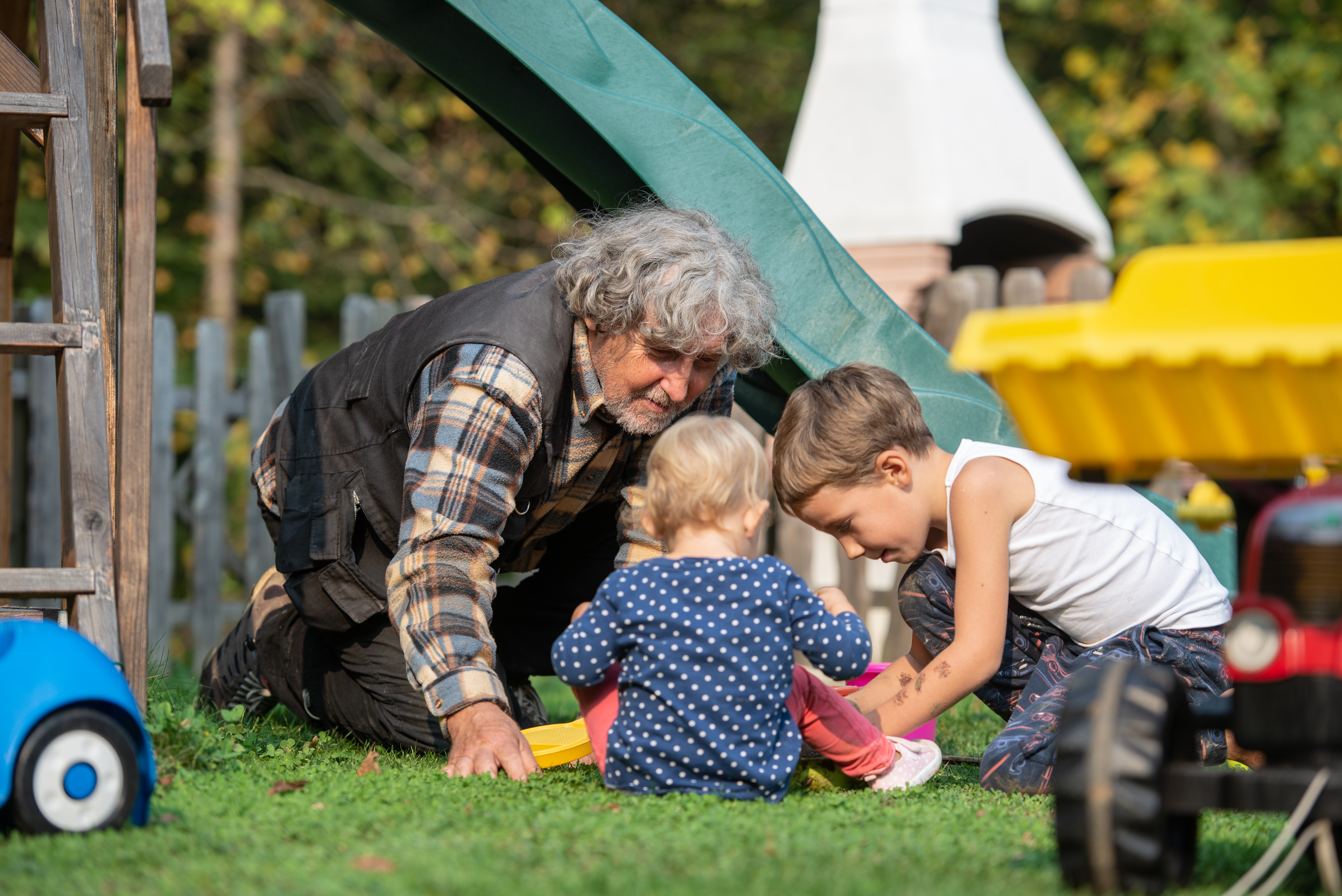 An older adult plays on the ground with two small children