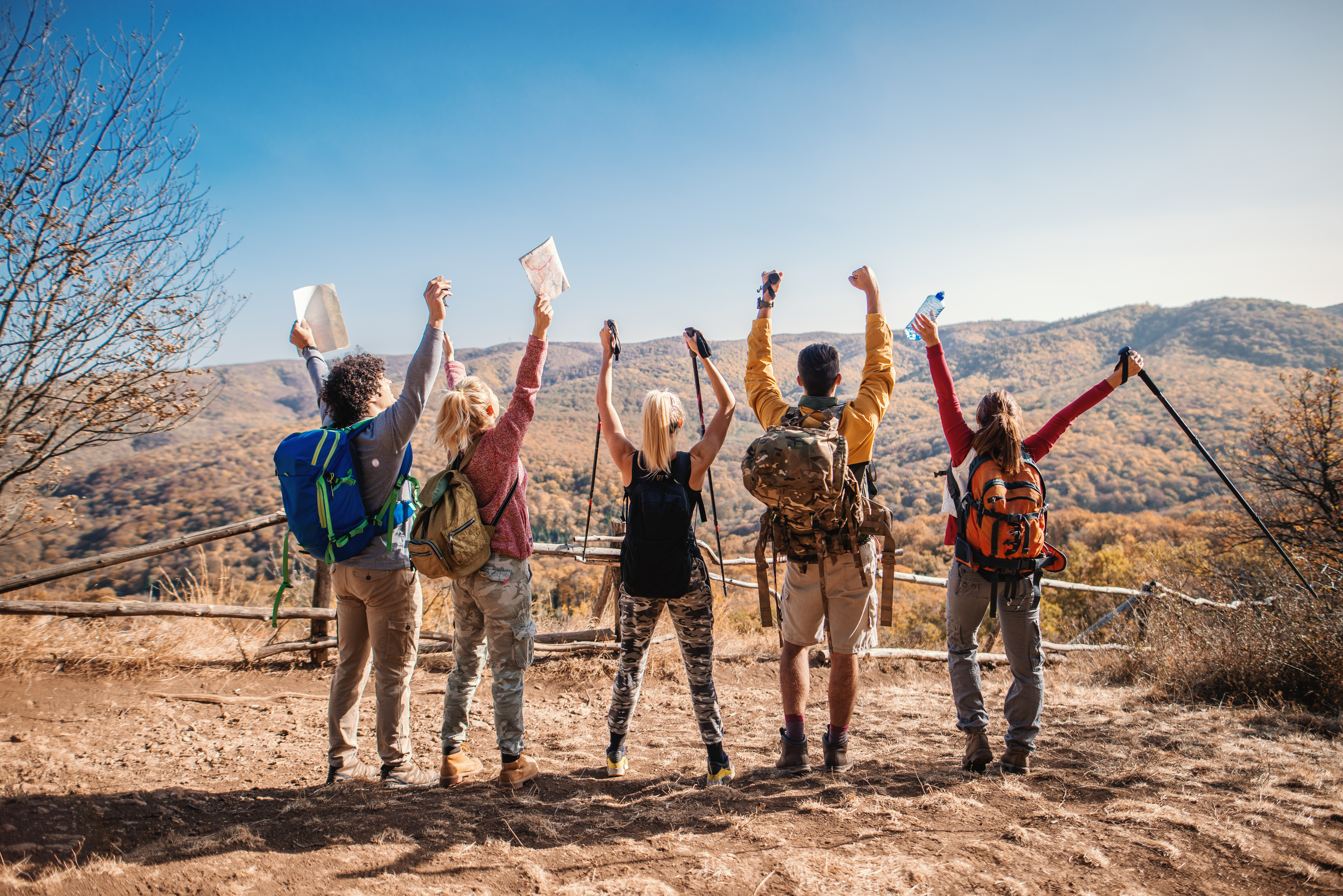 A group of youth stand with their backs to the camera and arms raised