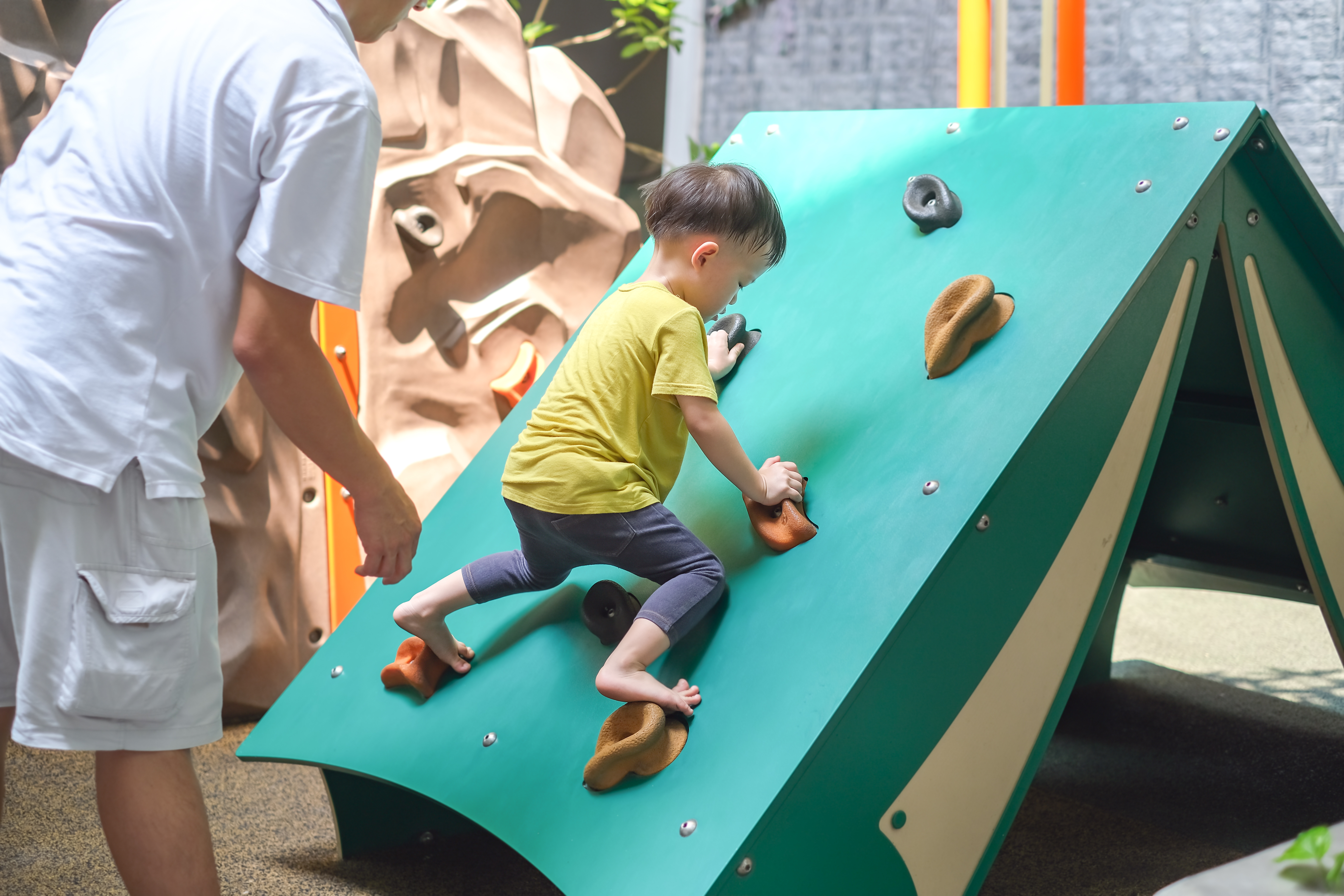 a young boy climbs on a rock wall