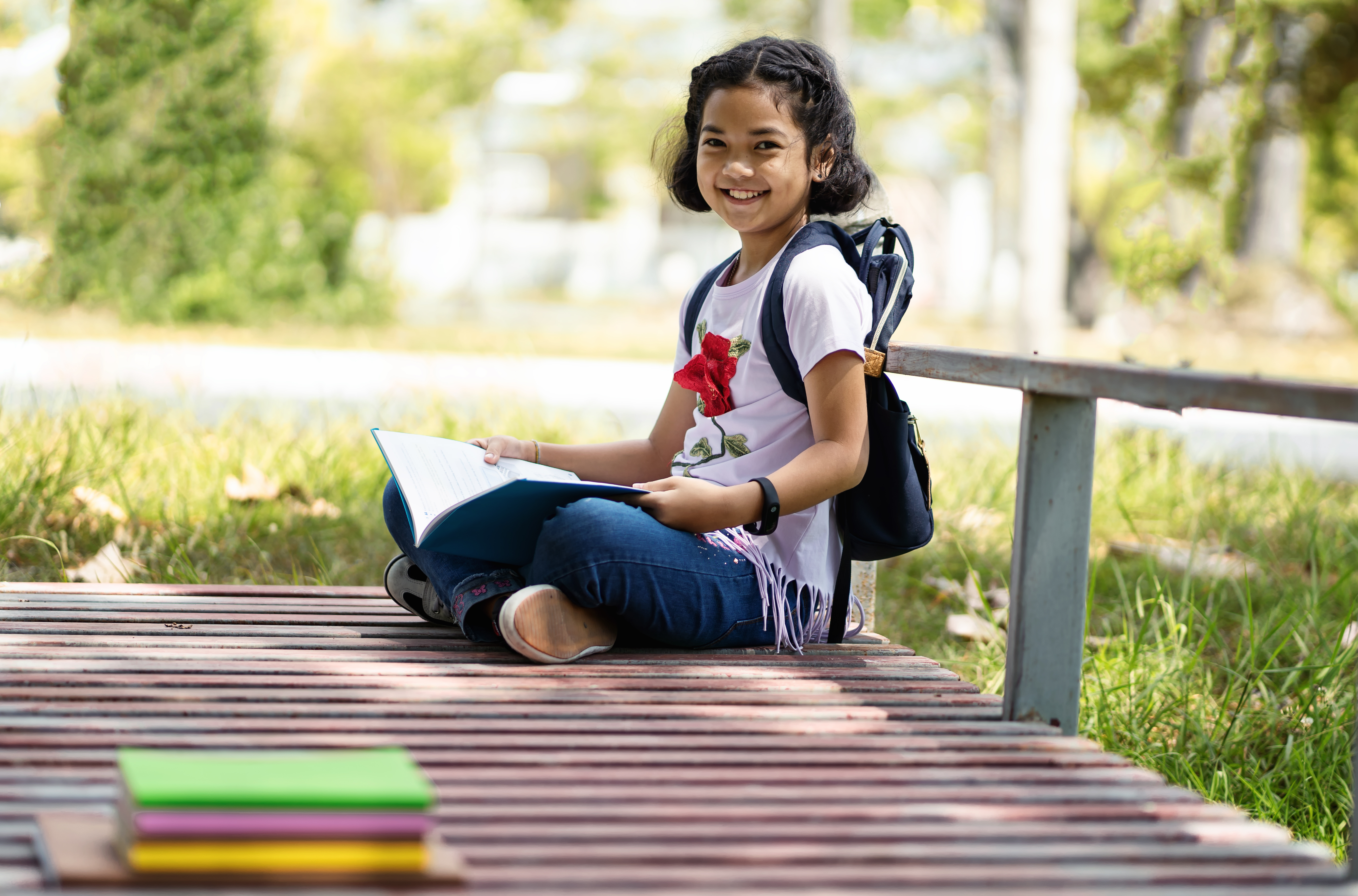 A child sits outside holding a book