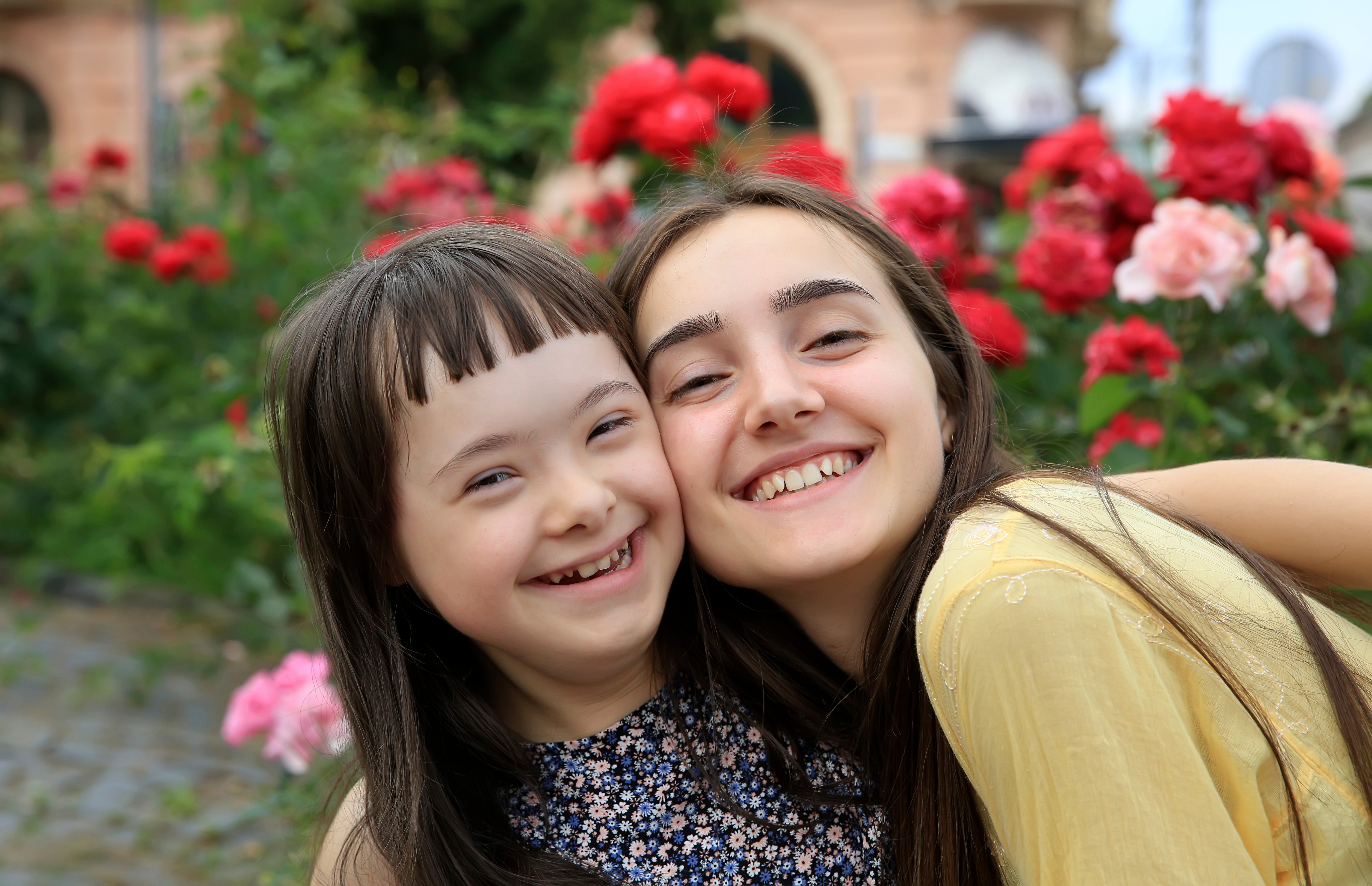 two young people hug and smile in a garden