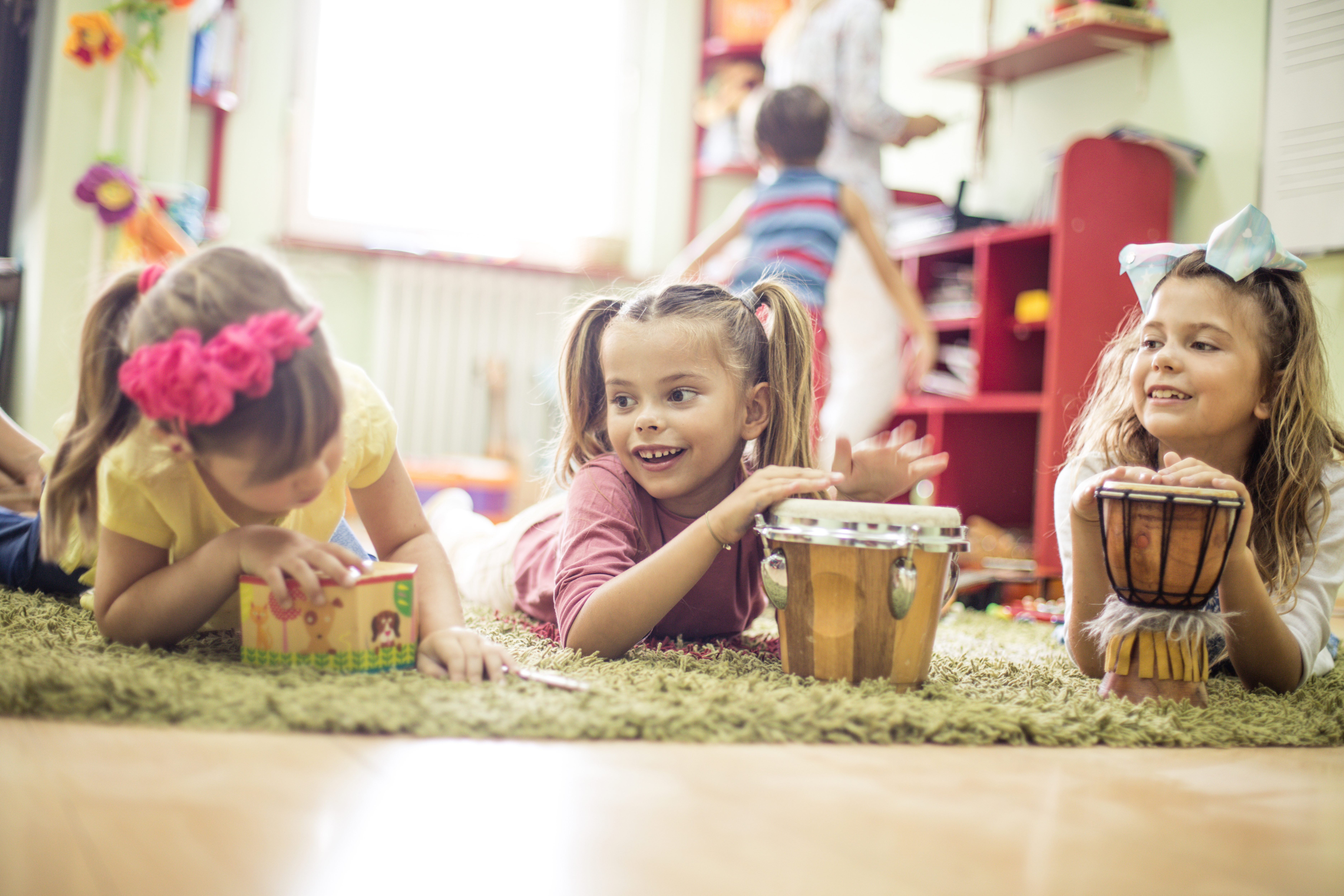 three kids sitting on the floor playing drums