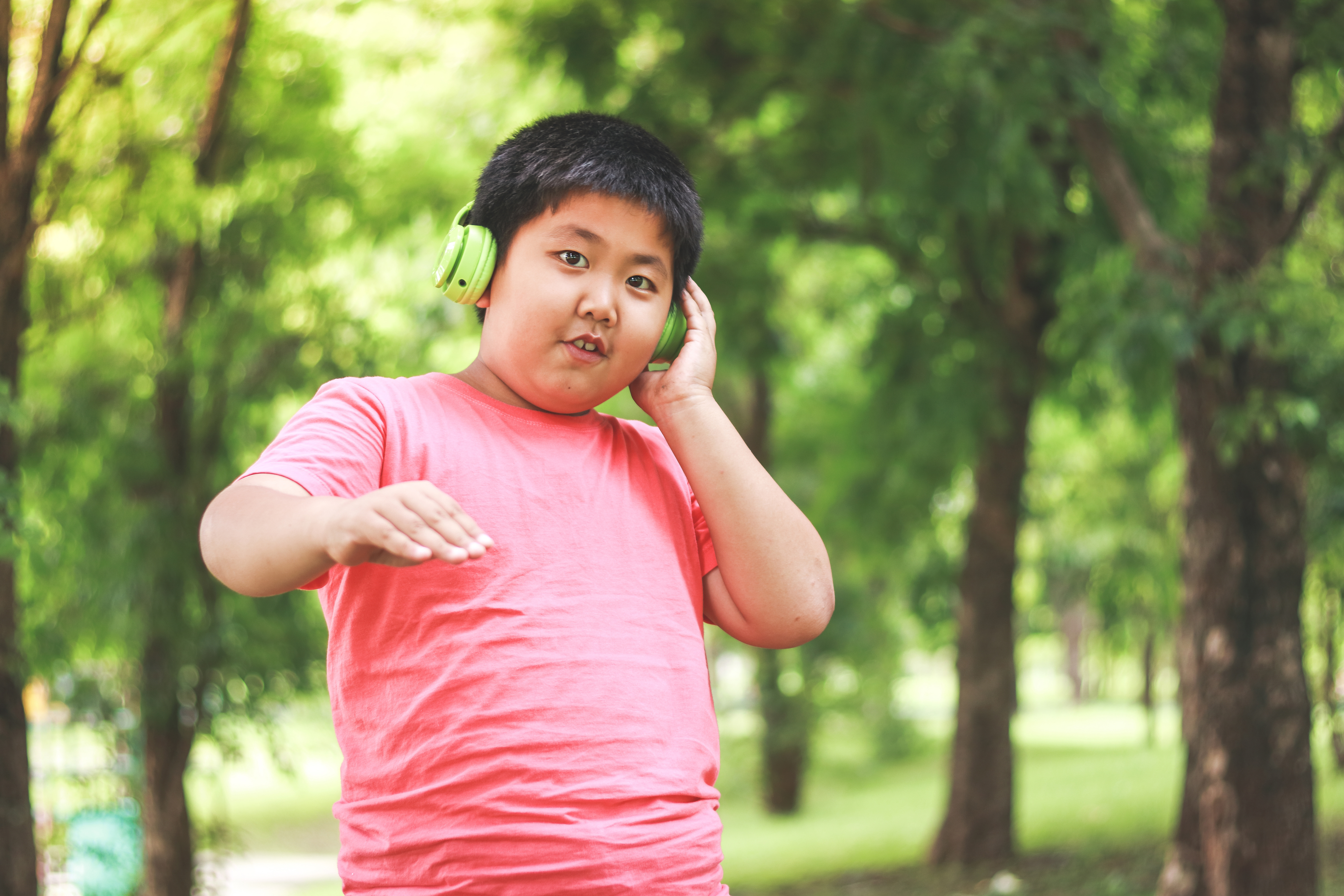 A young person walks through a park while listening through headphones