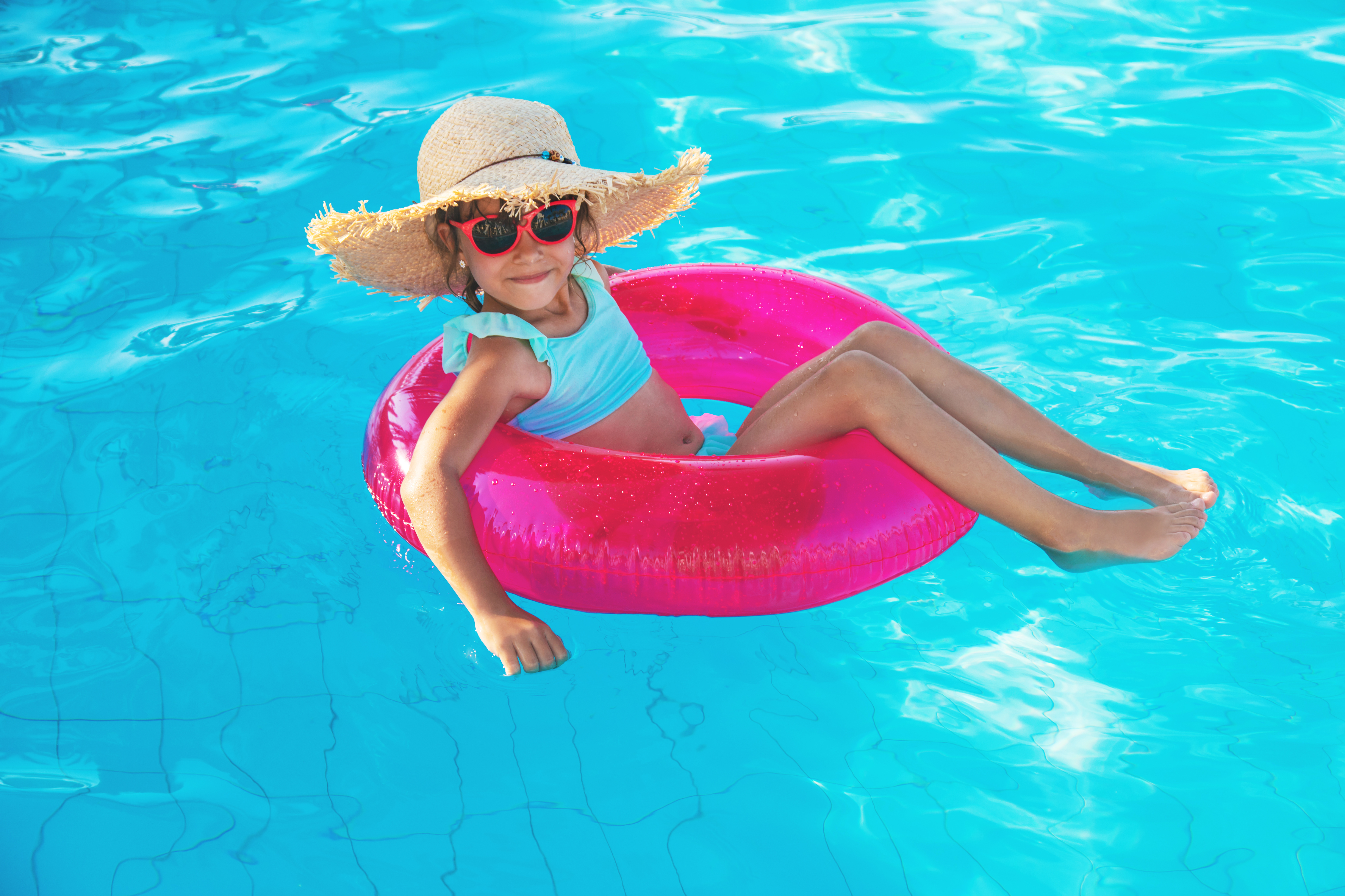 a child floats in a pool on an innertube