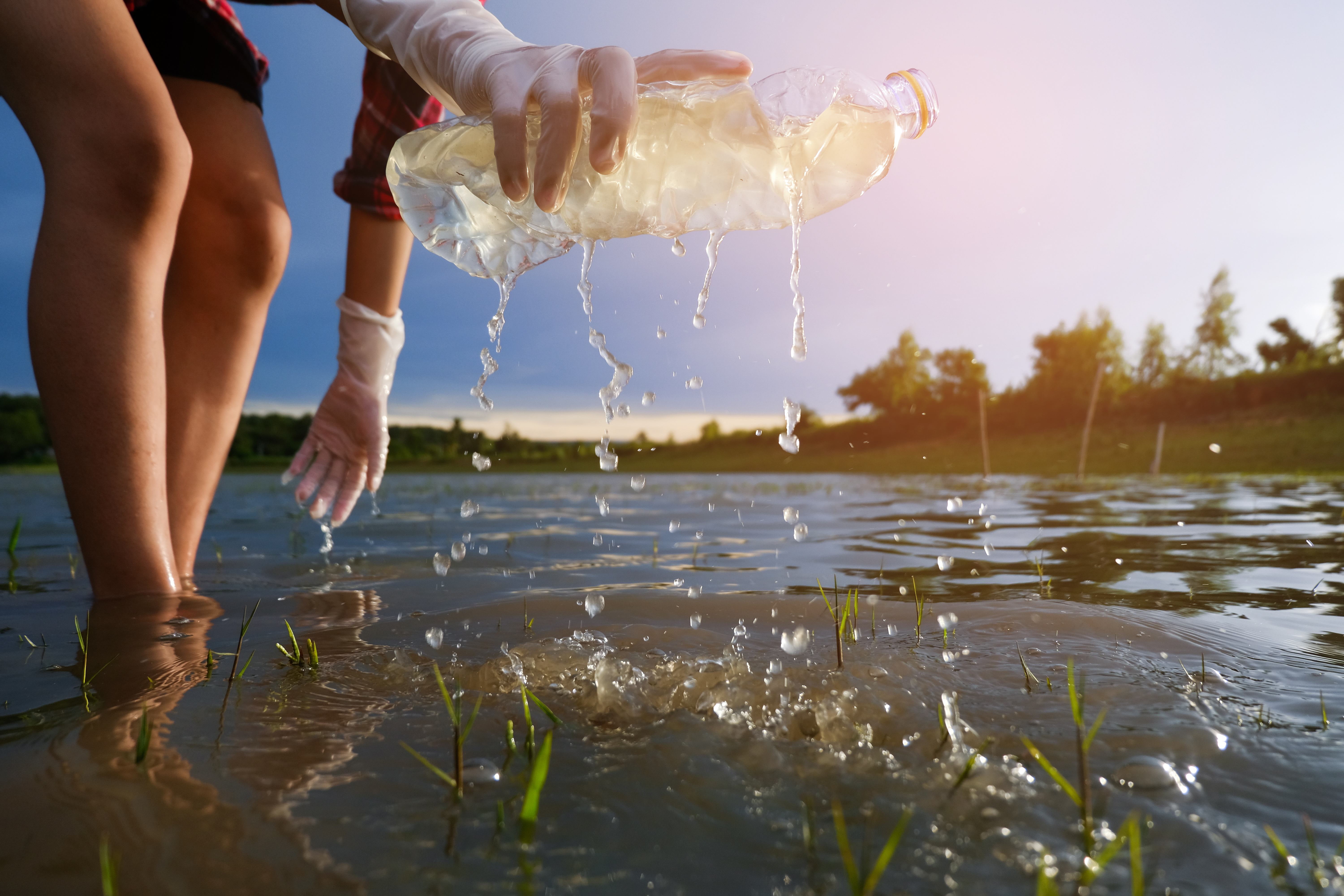 Someone picks trash up out of some water