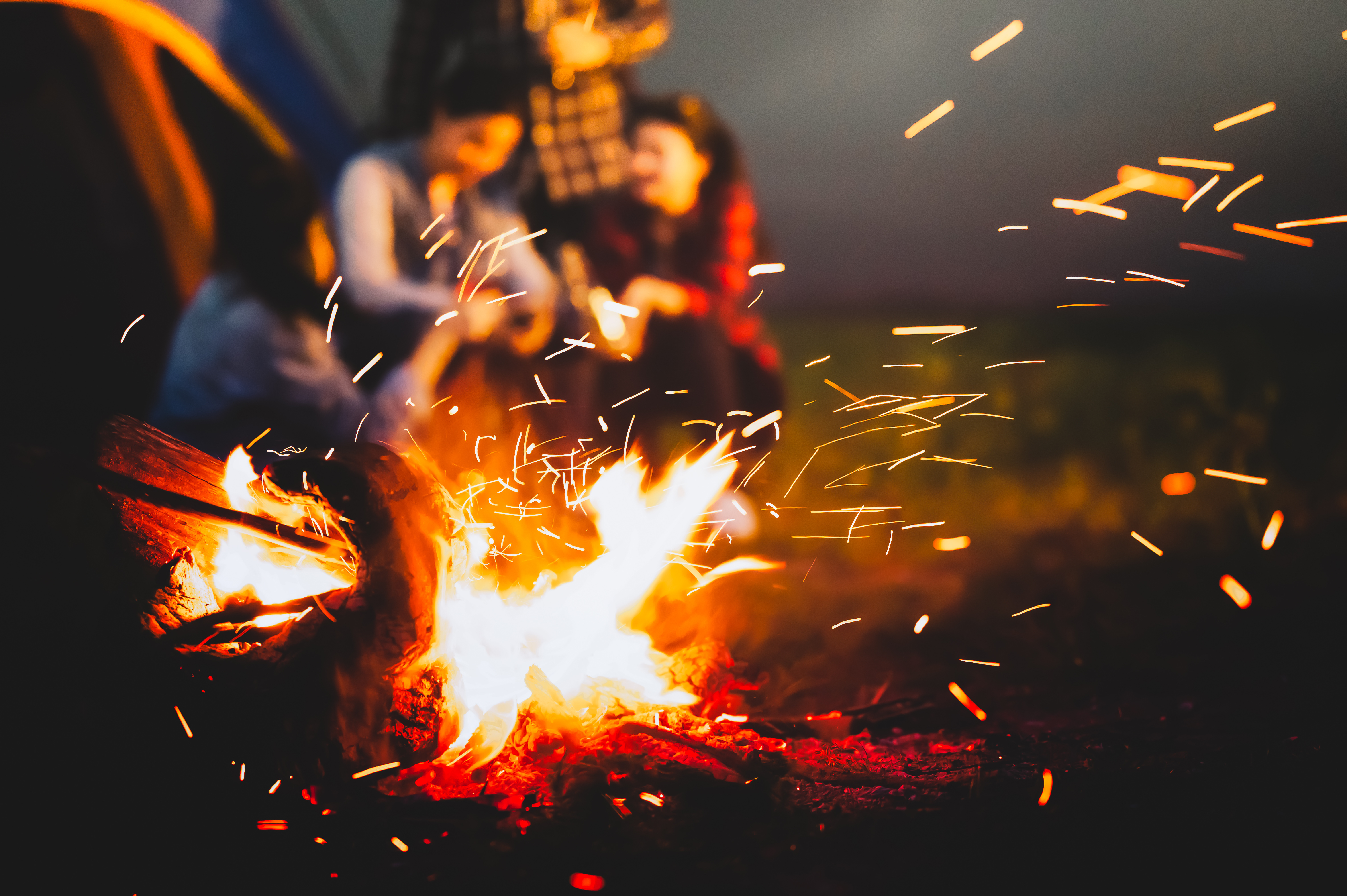 People sit outside near a fire.