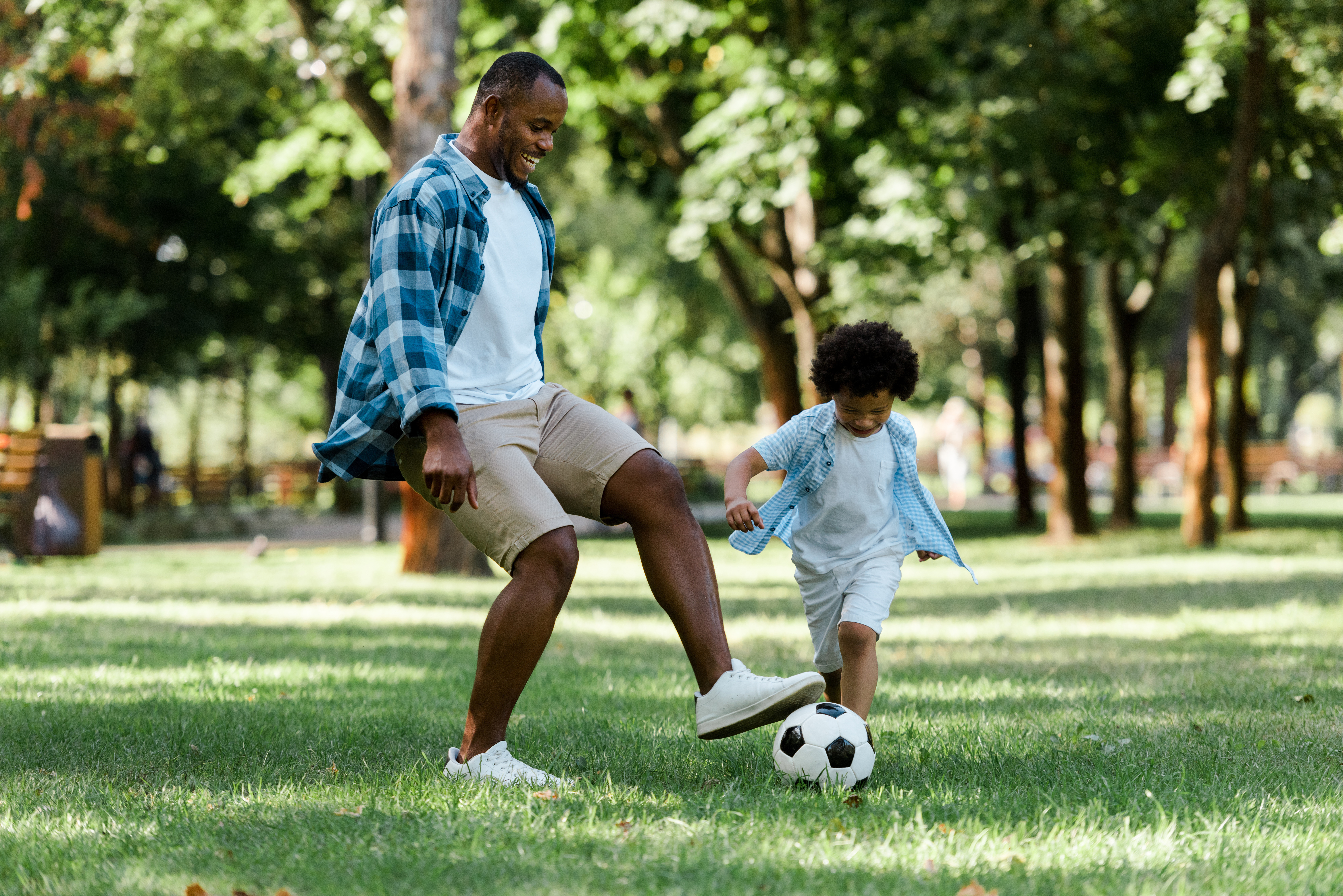 a man and boy play soccer in a park