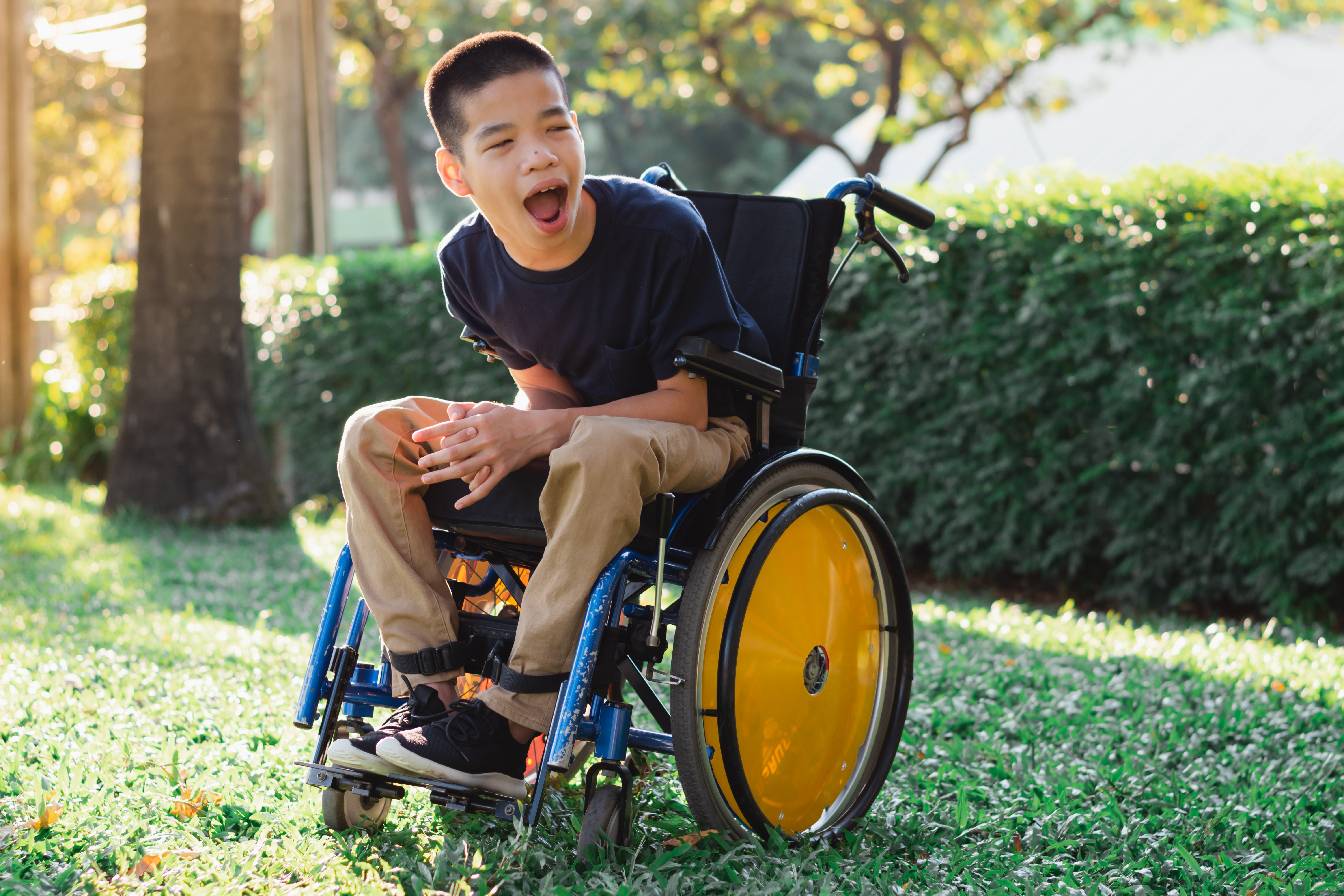 a young man in a wheelchair sits outside in the sunshine