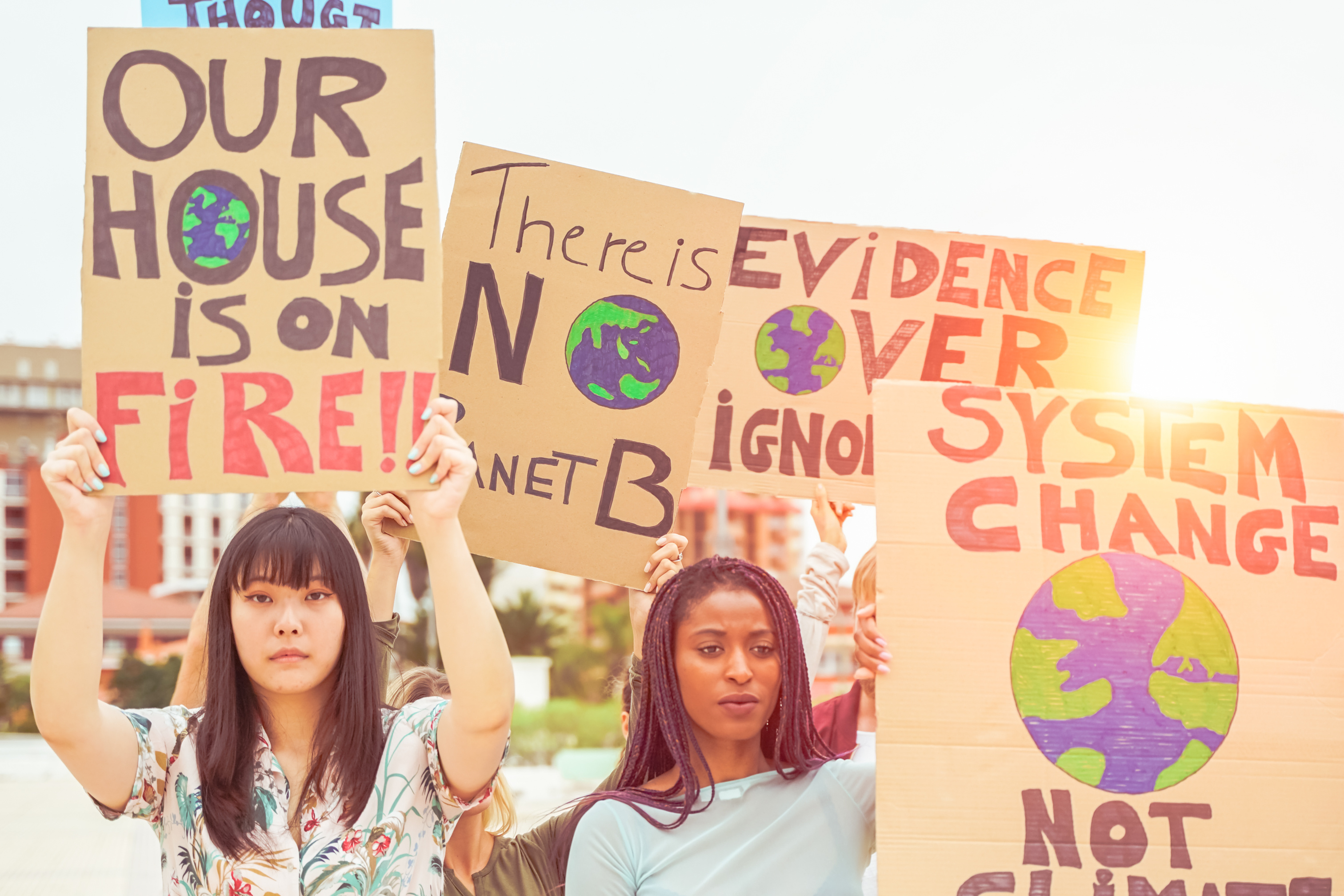 A group of youth stand together with signs about climate change
