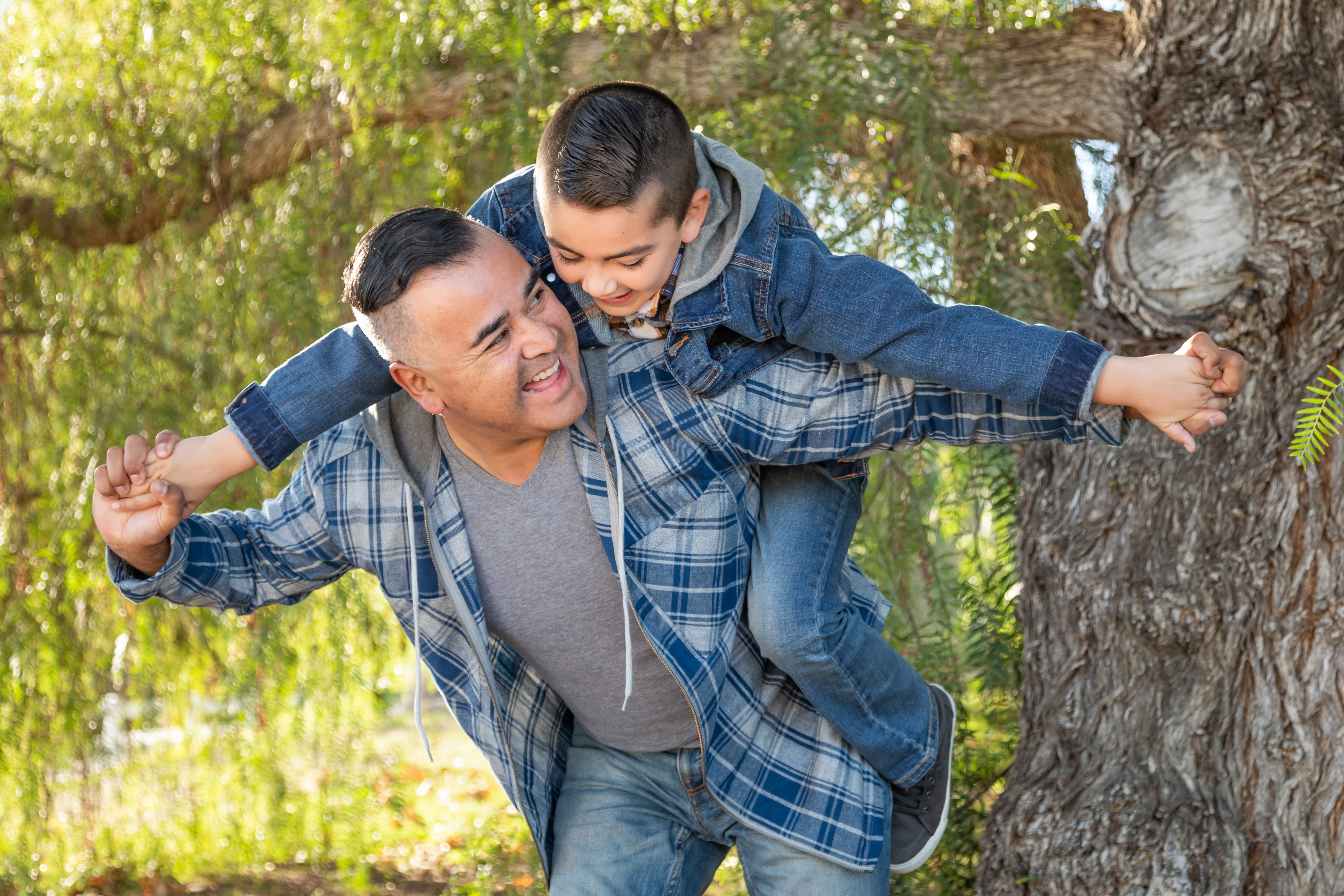 A boy rides on his dad's back in a park