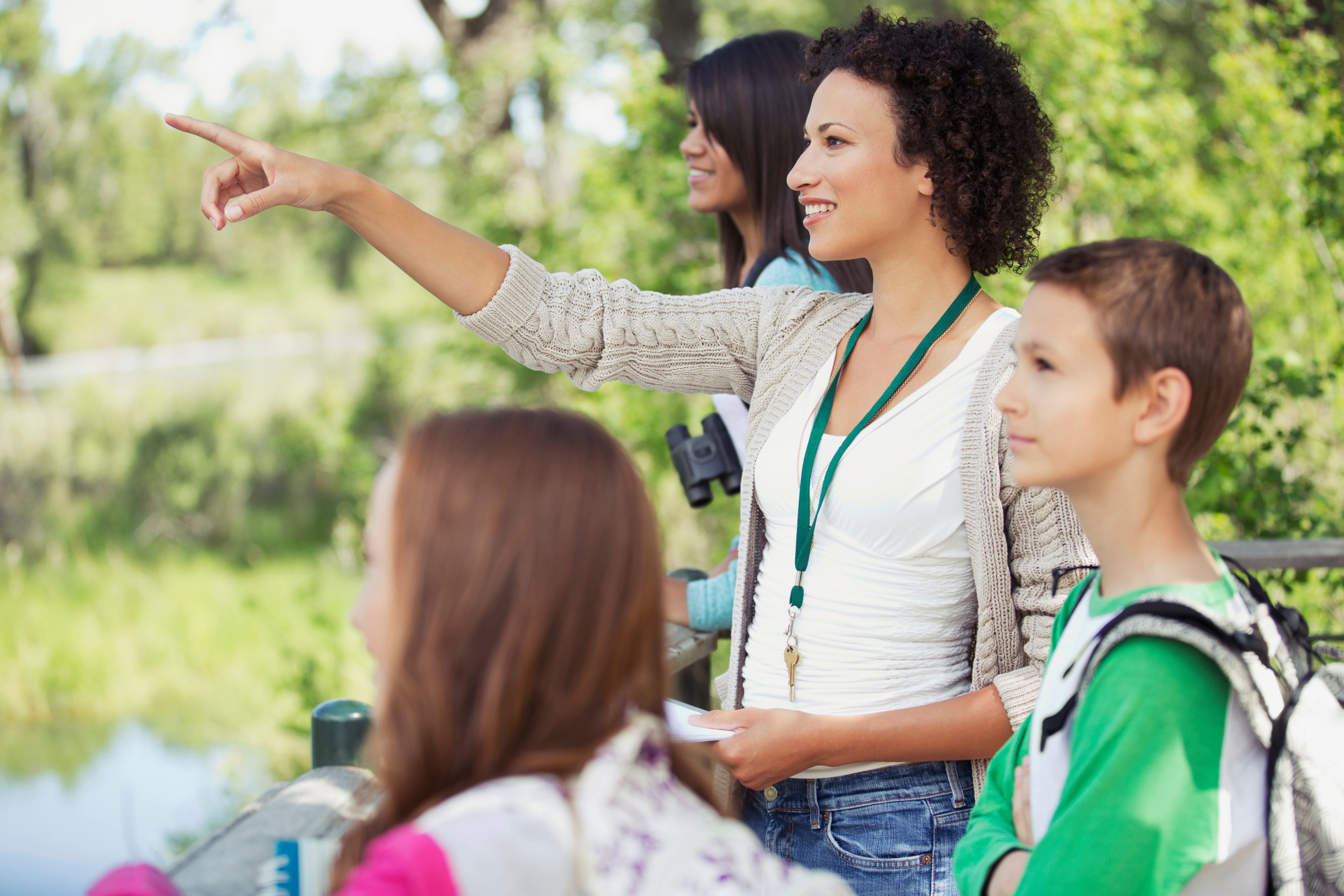 A group of students and teachers look for birds near a pond