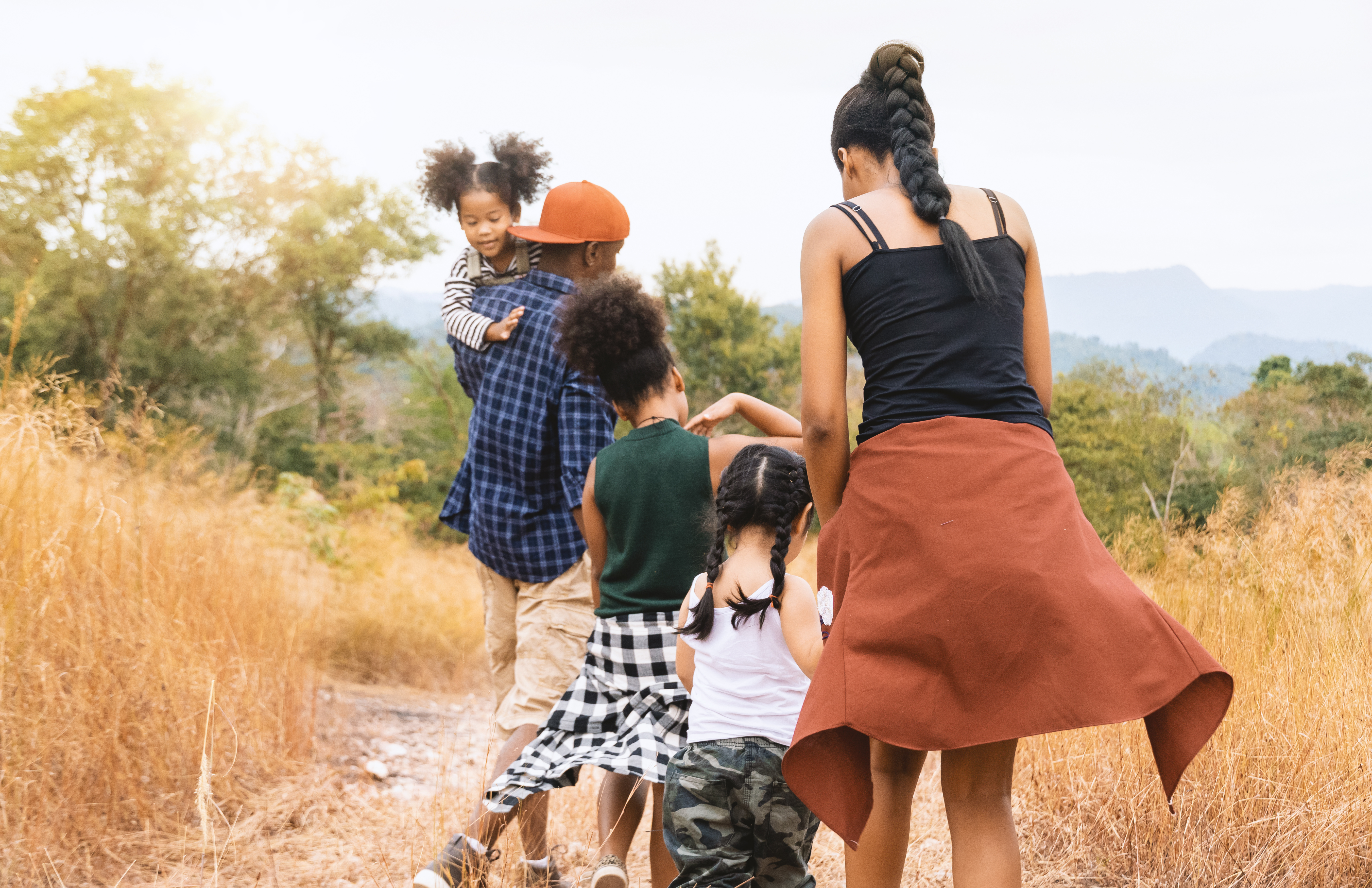 a family with several children walks along a trail together in dry grass