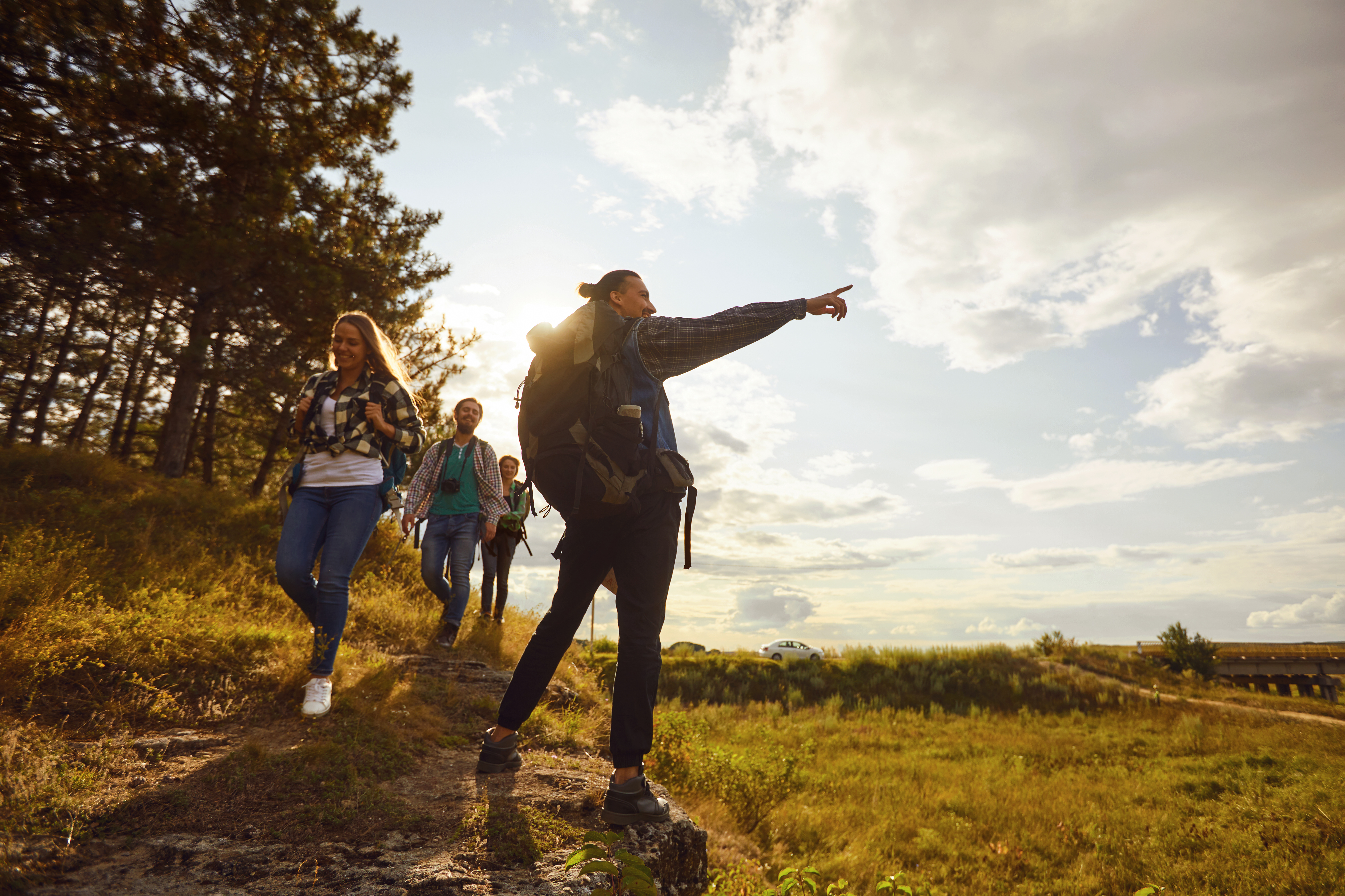 a group of people walk down a trail wearing backpacks