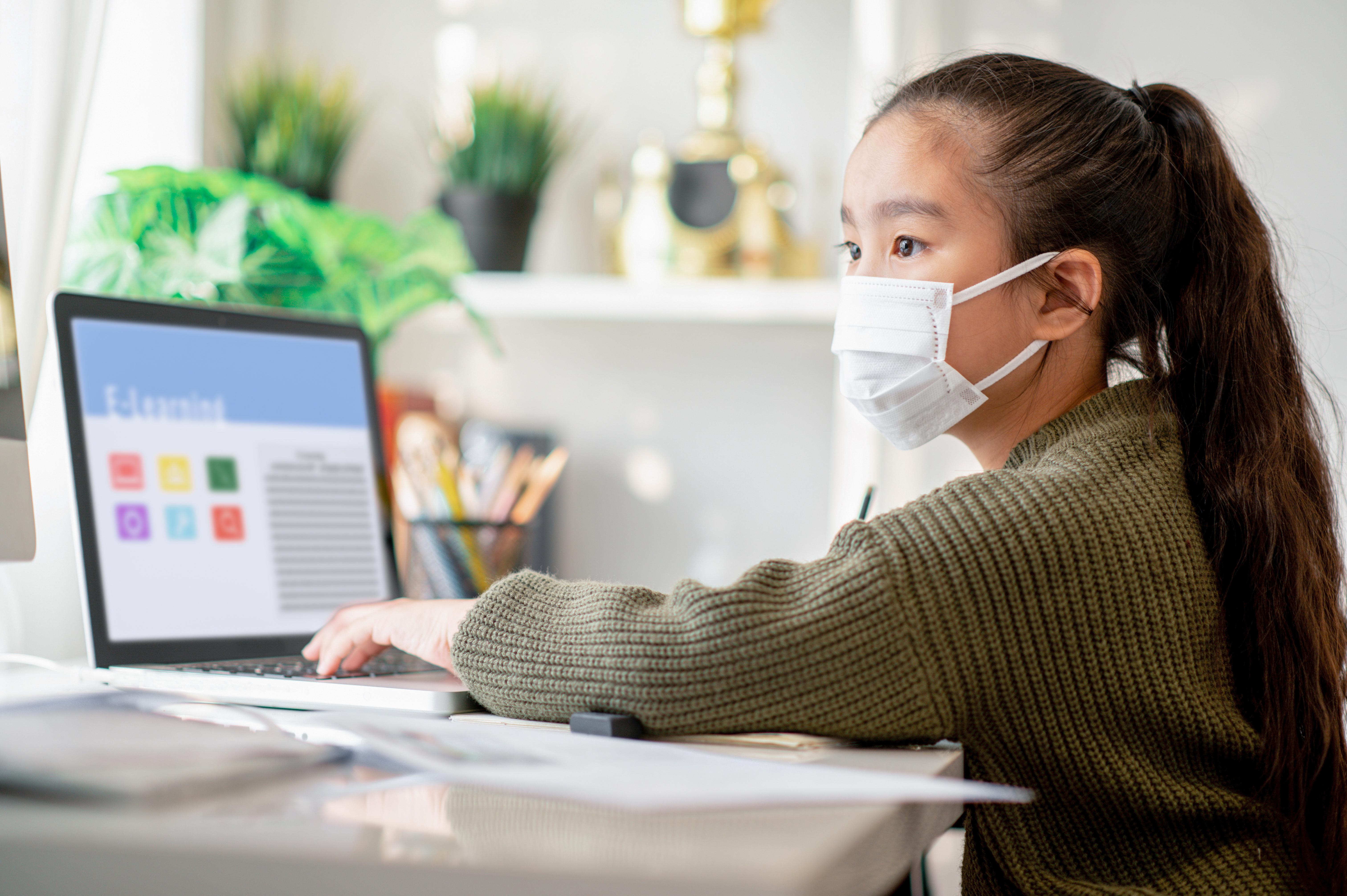 student studies at computer in a mask