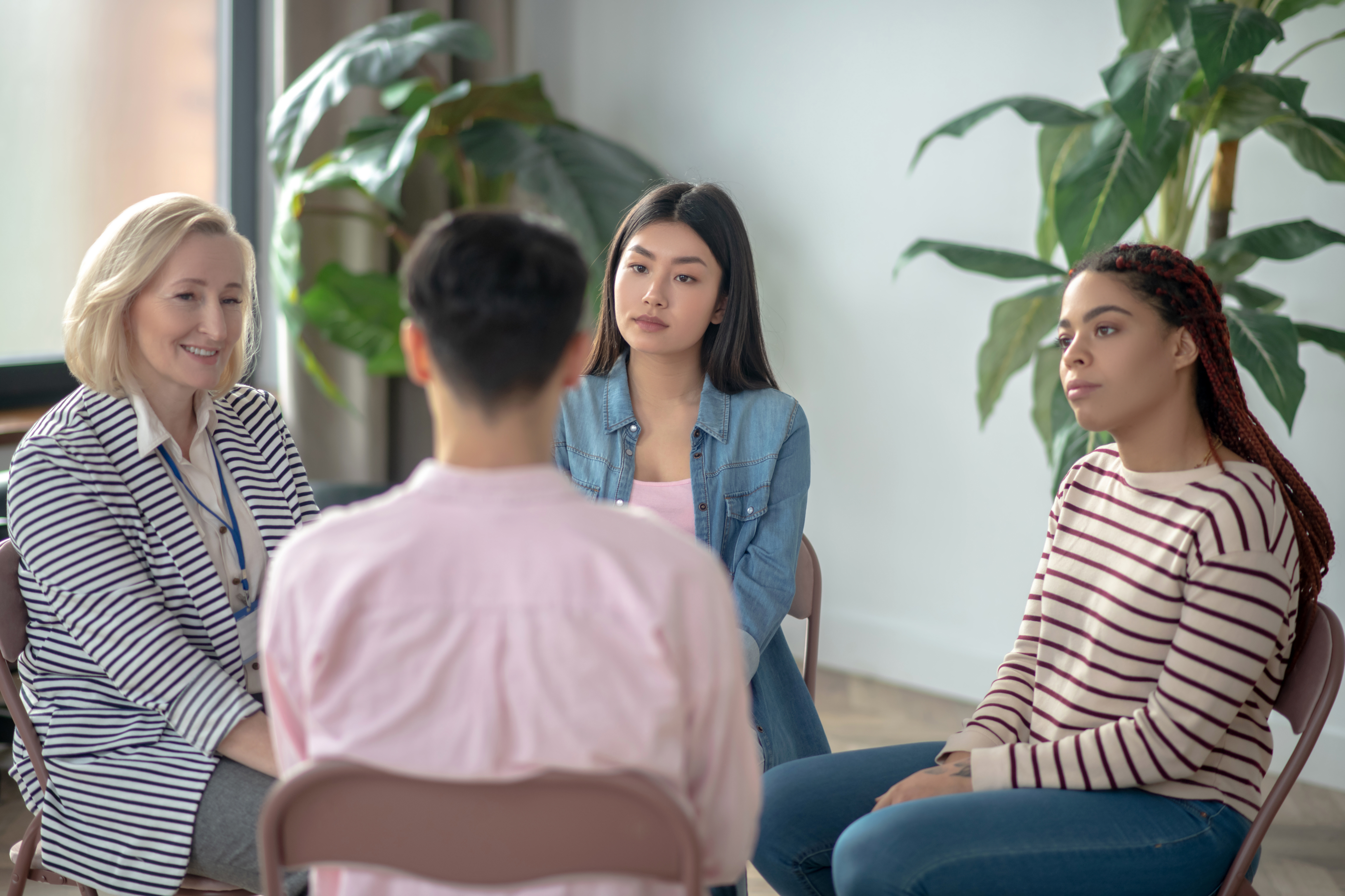 Several young people sit in a circle with an adult