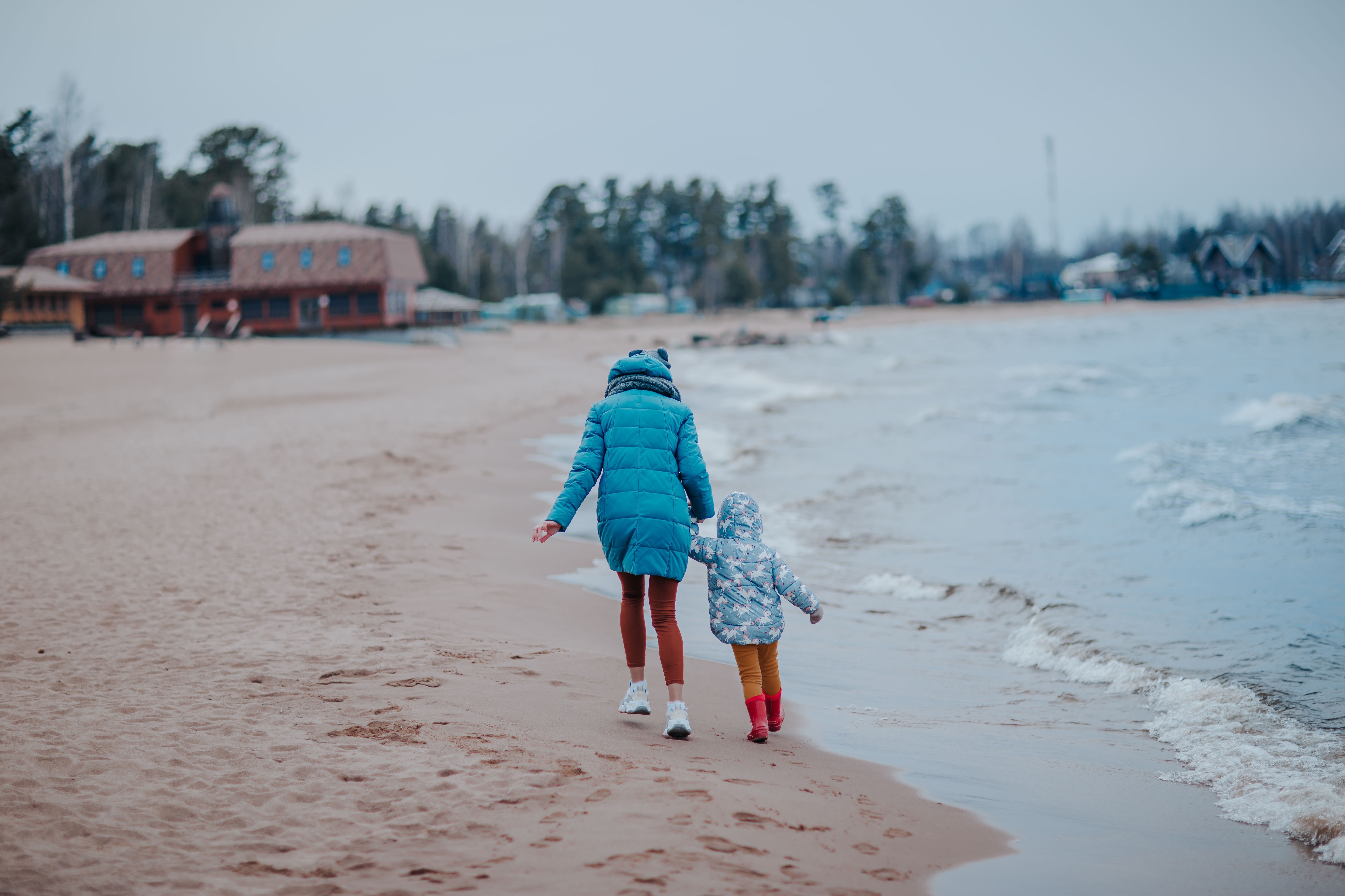 adult and child walking down a beach