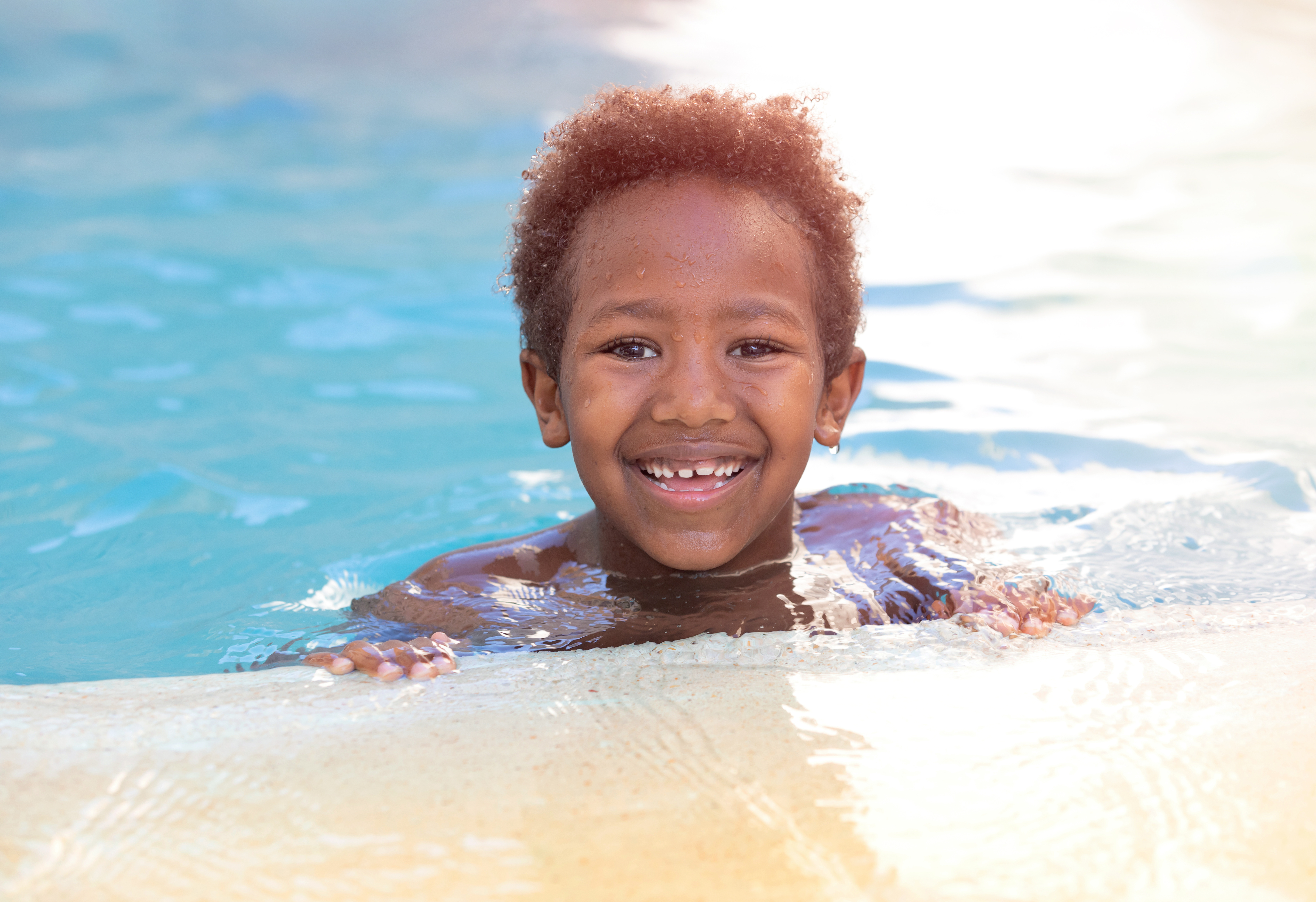 A child smiles from the pool