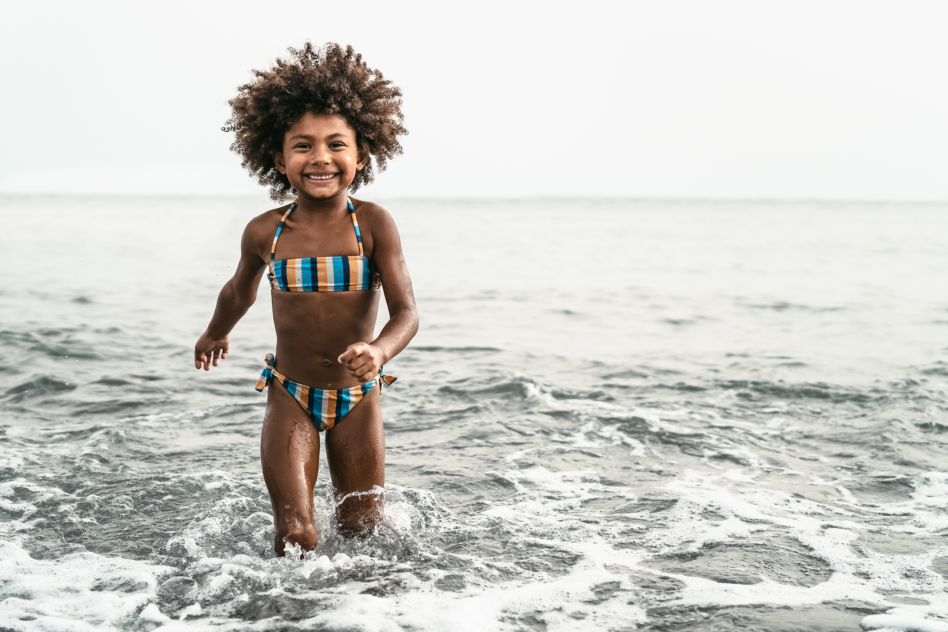 a child in a bathing suit runs out of the water