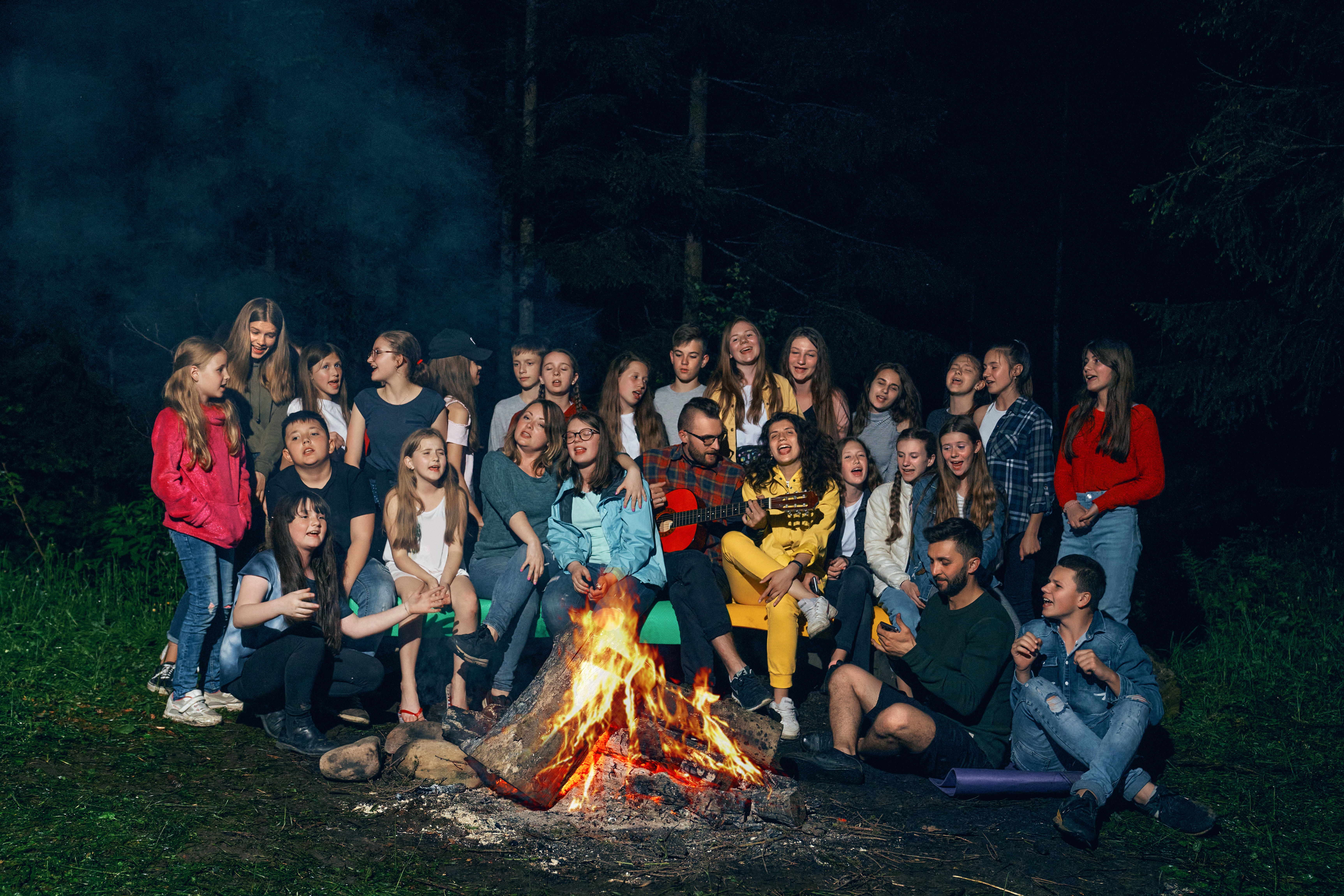 a group of kids poses around a campfire