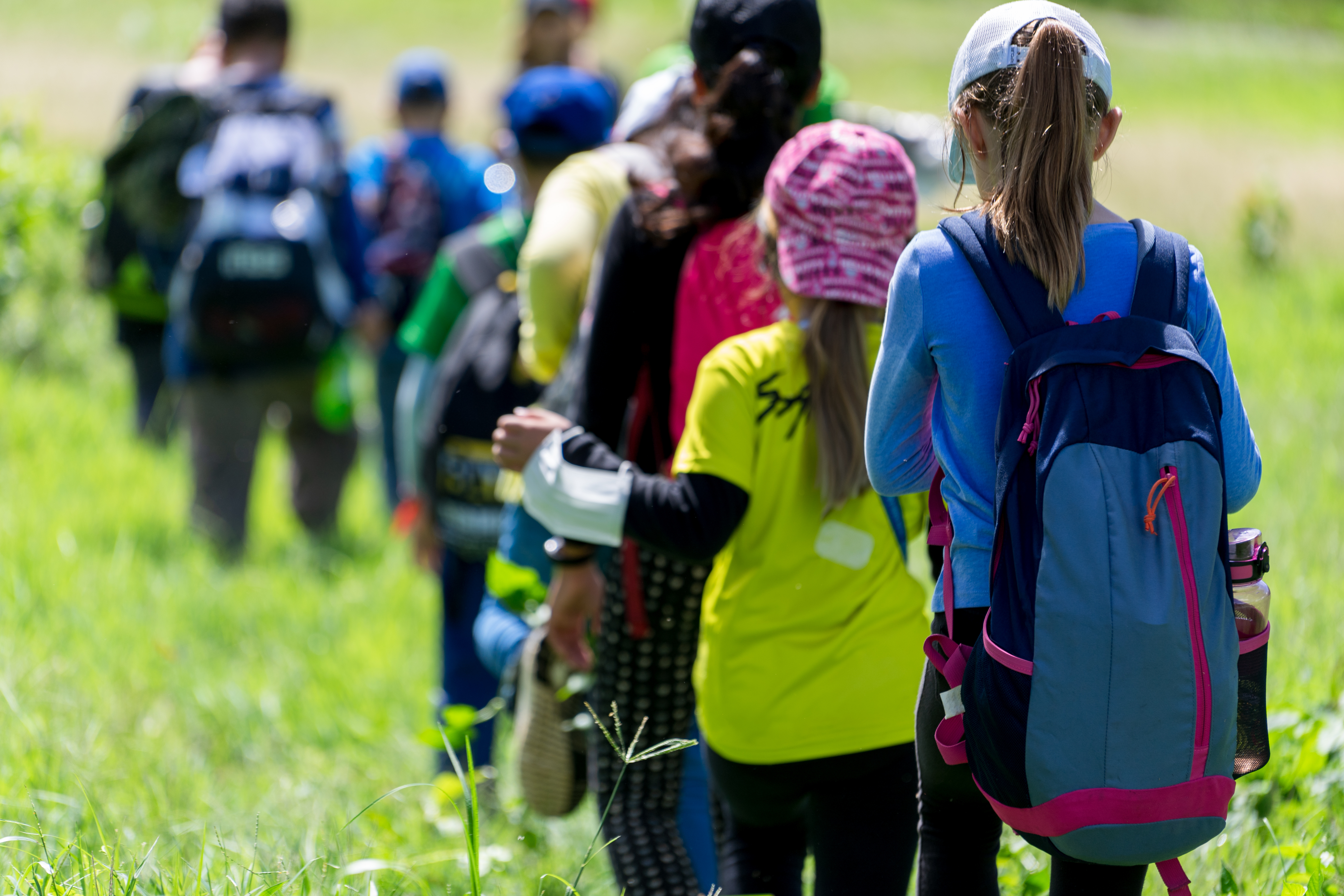 A group of young people hike through a field together
