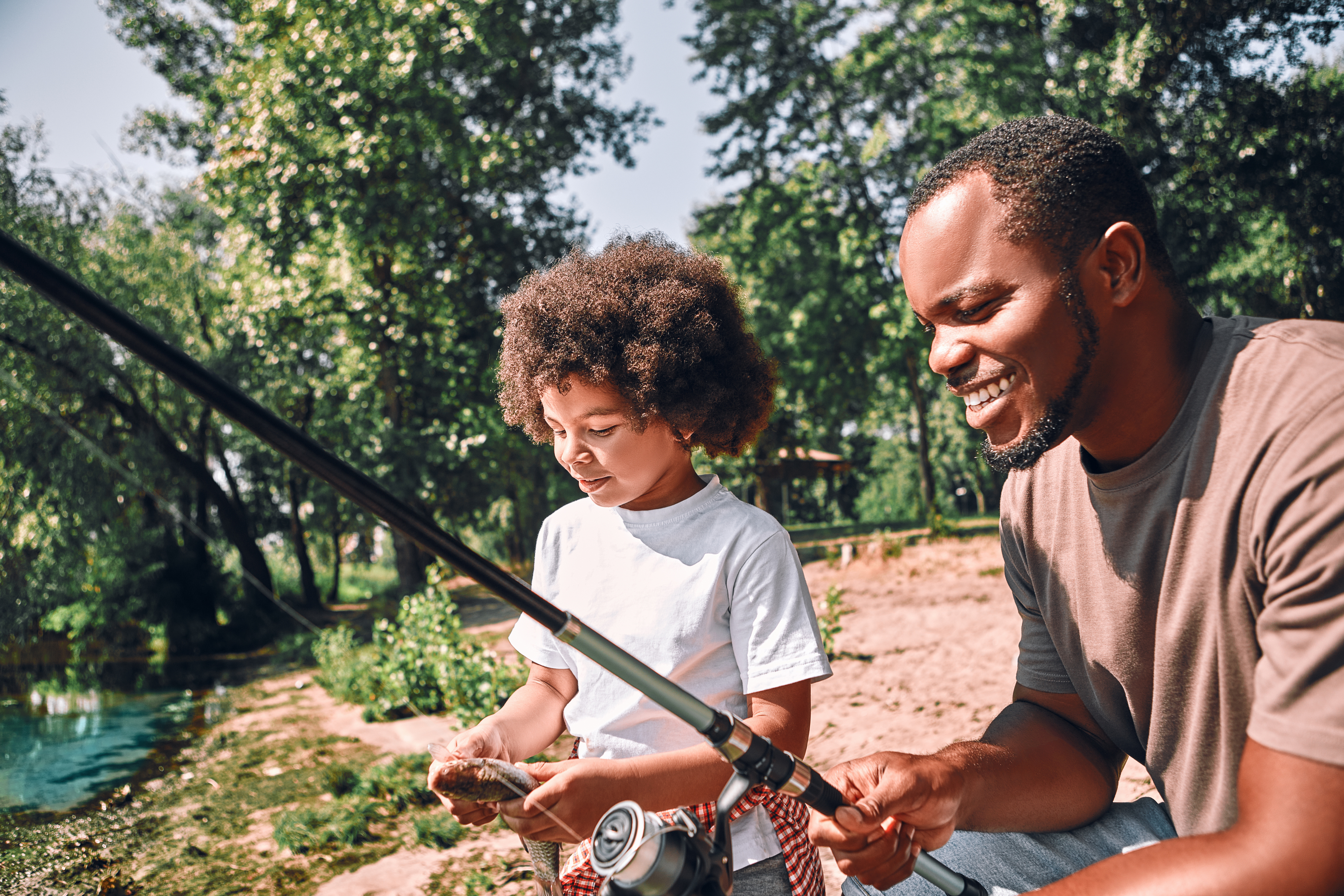 a child and a man fish together on a sunny day