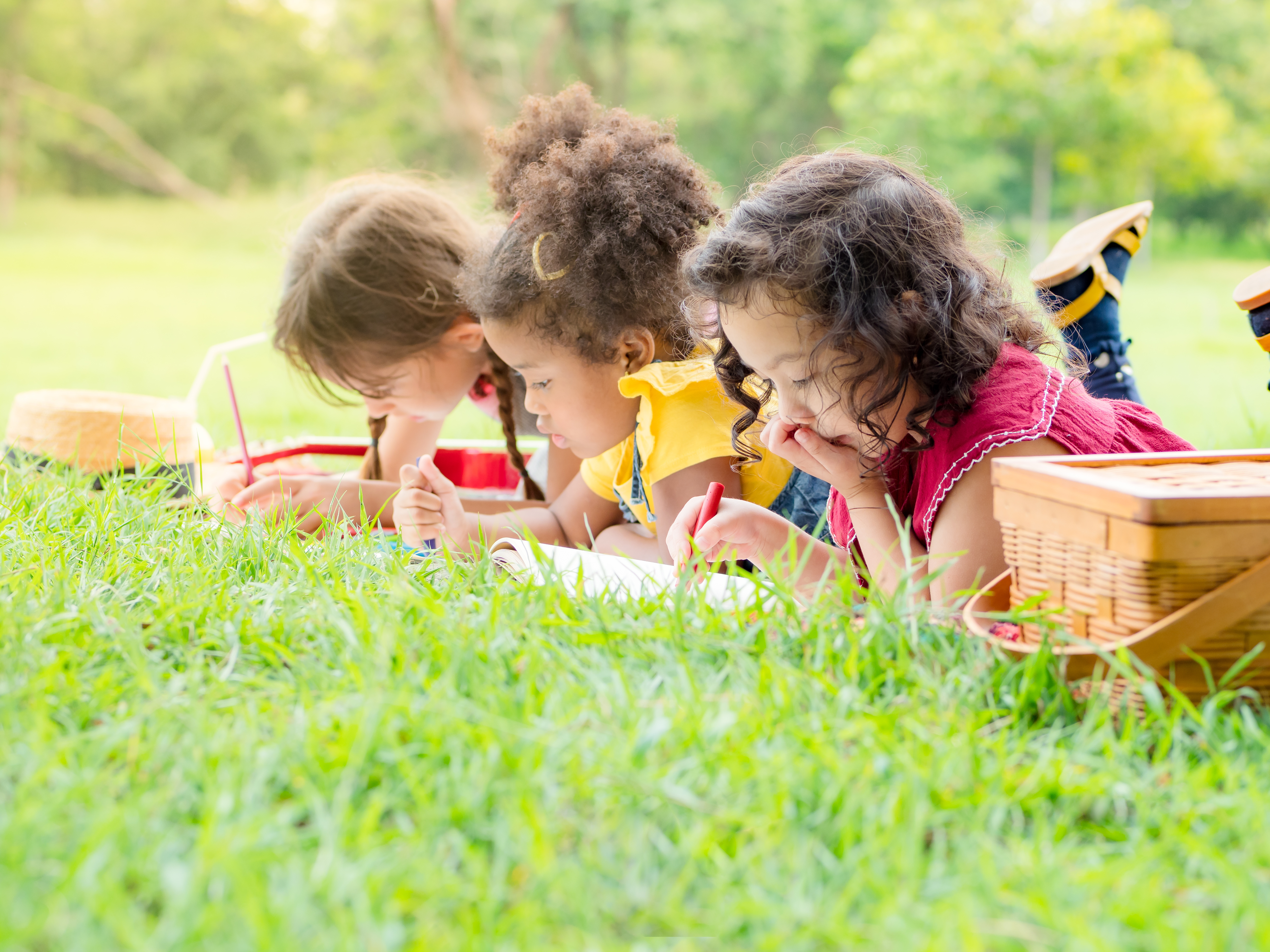 Three children lay on the grass drawing