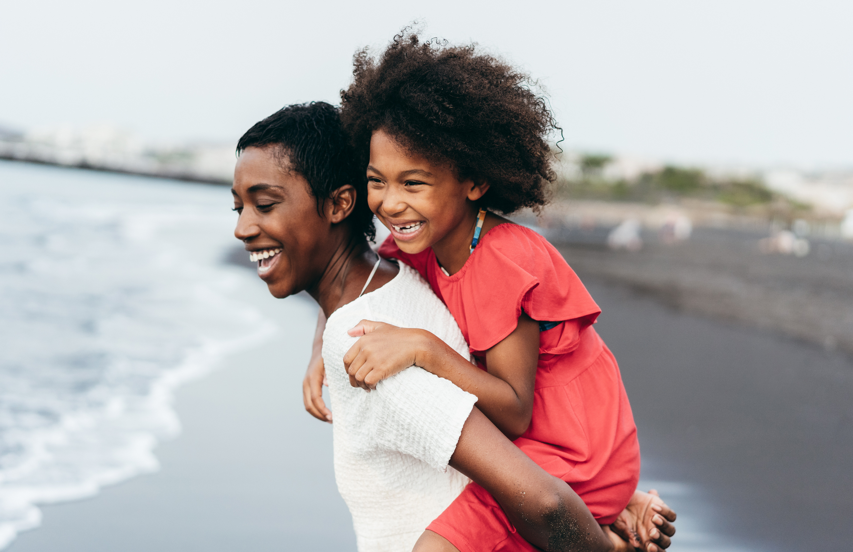 mother and daughter laughing on a beach