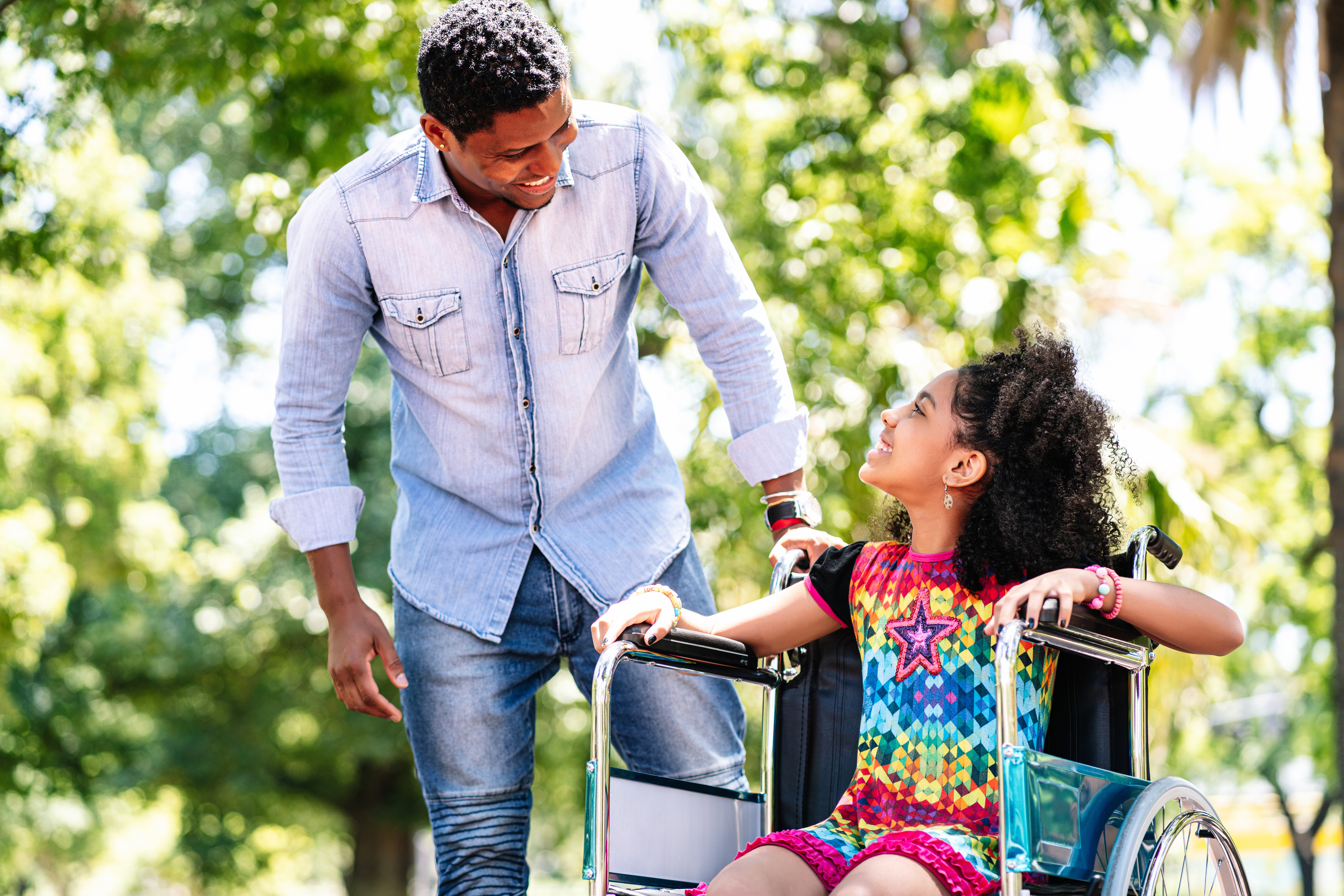 An adult and child smile at each other in a green park