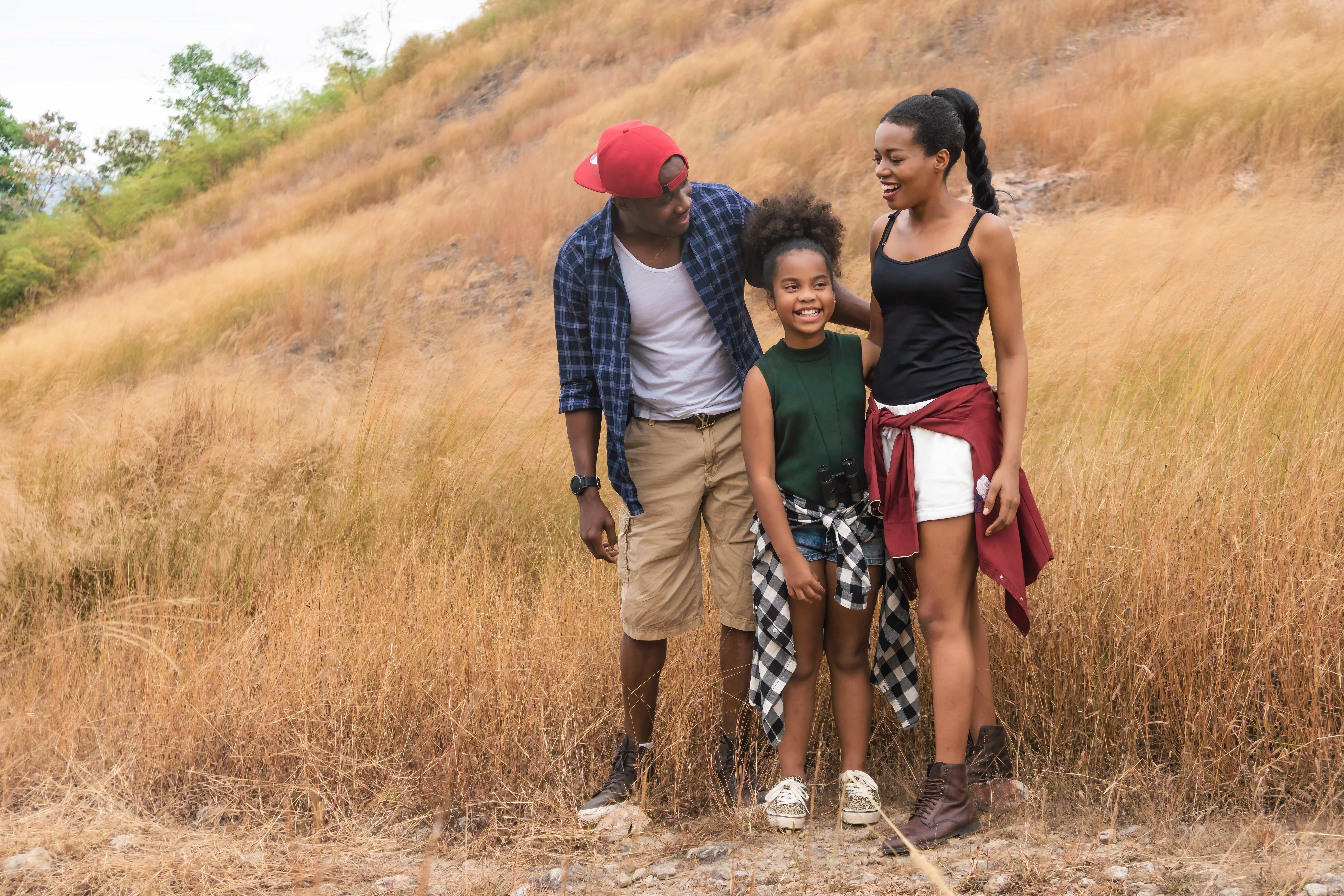 A child stands between two adults on a hiking trail