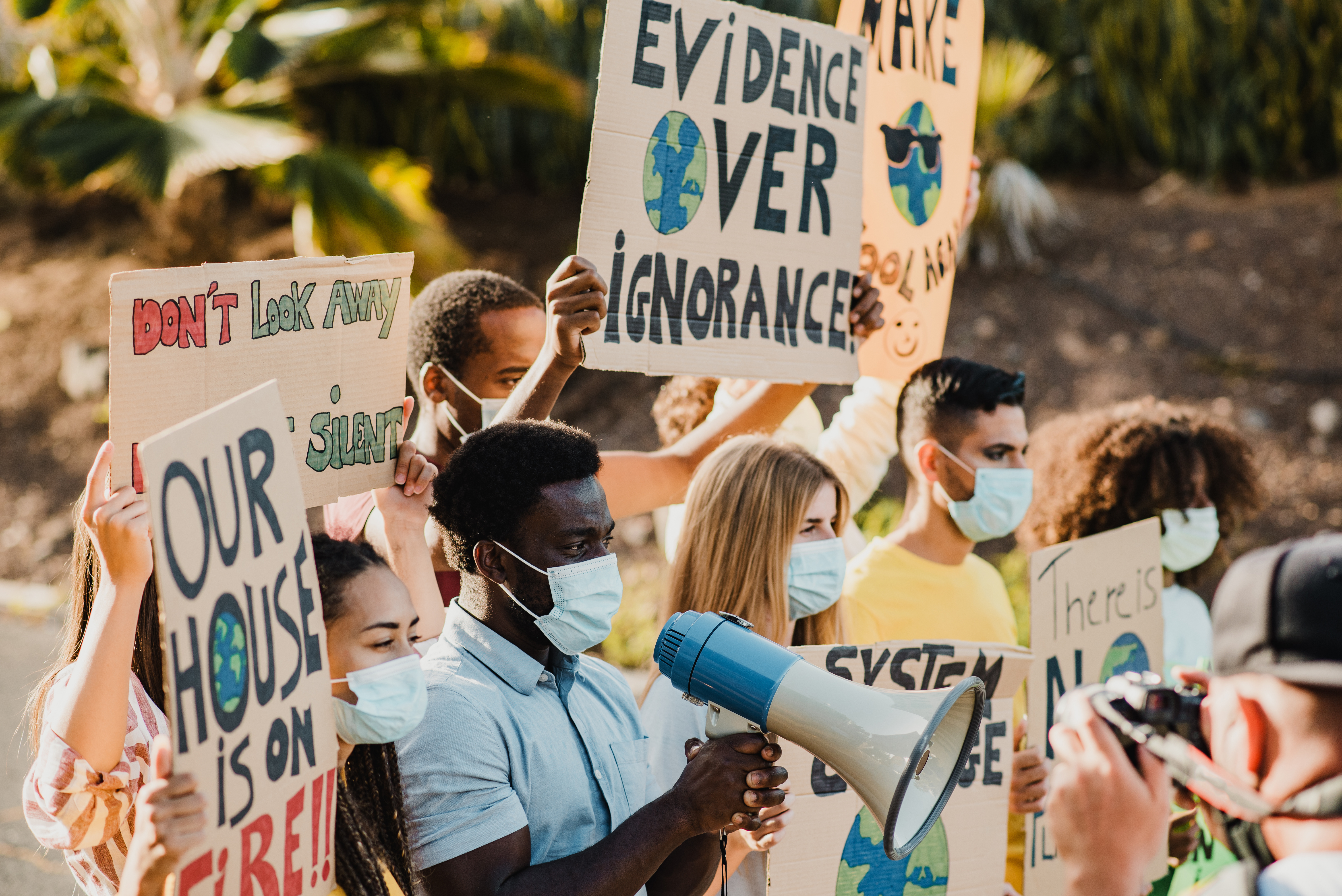 A group of young adults stand with signs about the environment and megaphones. 