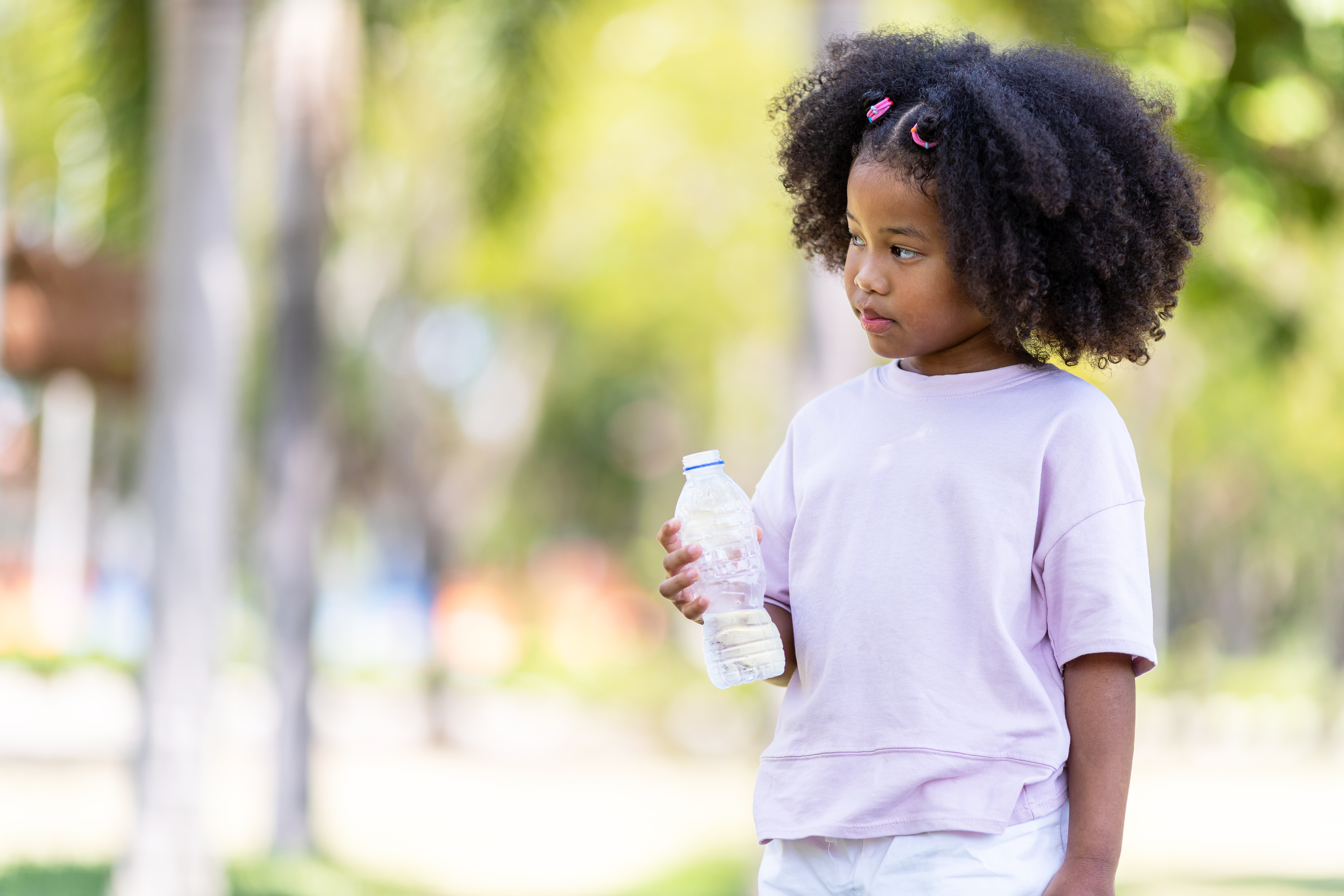 a young girl holds a water bottle on a hot day 