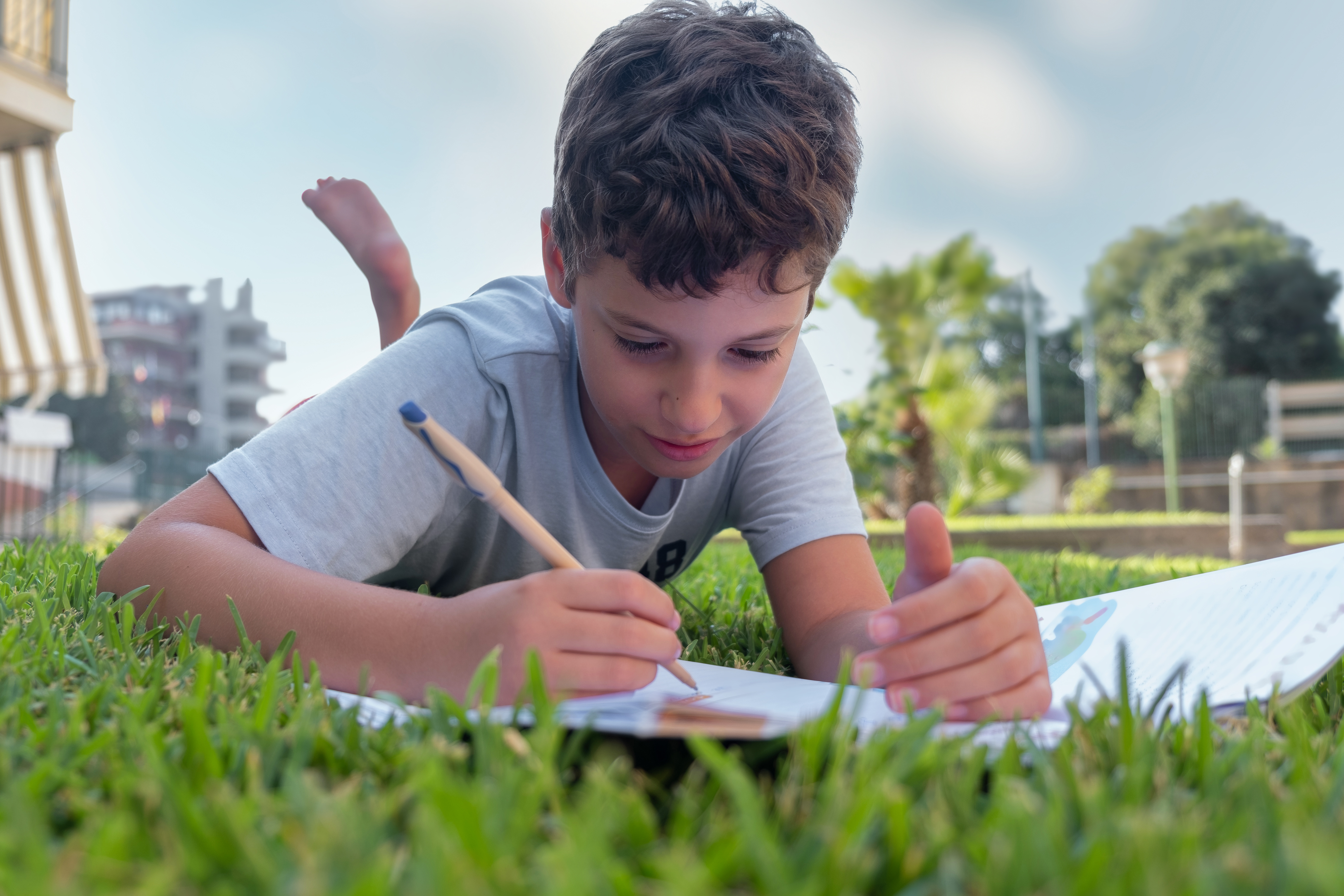 A child works in a notebook while laying in gradd