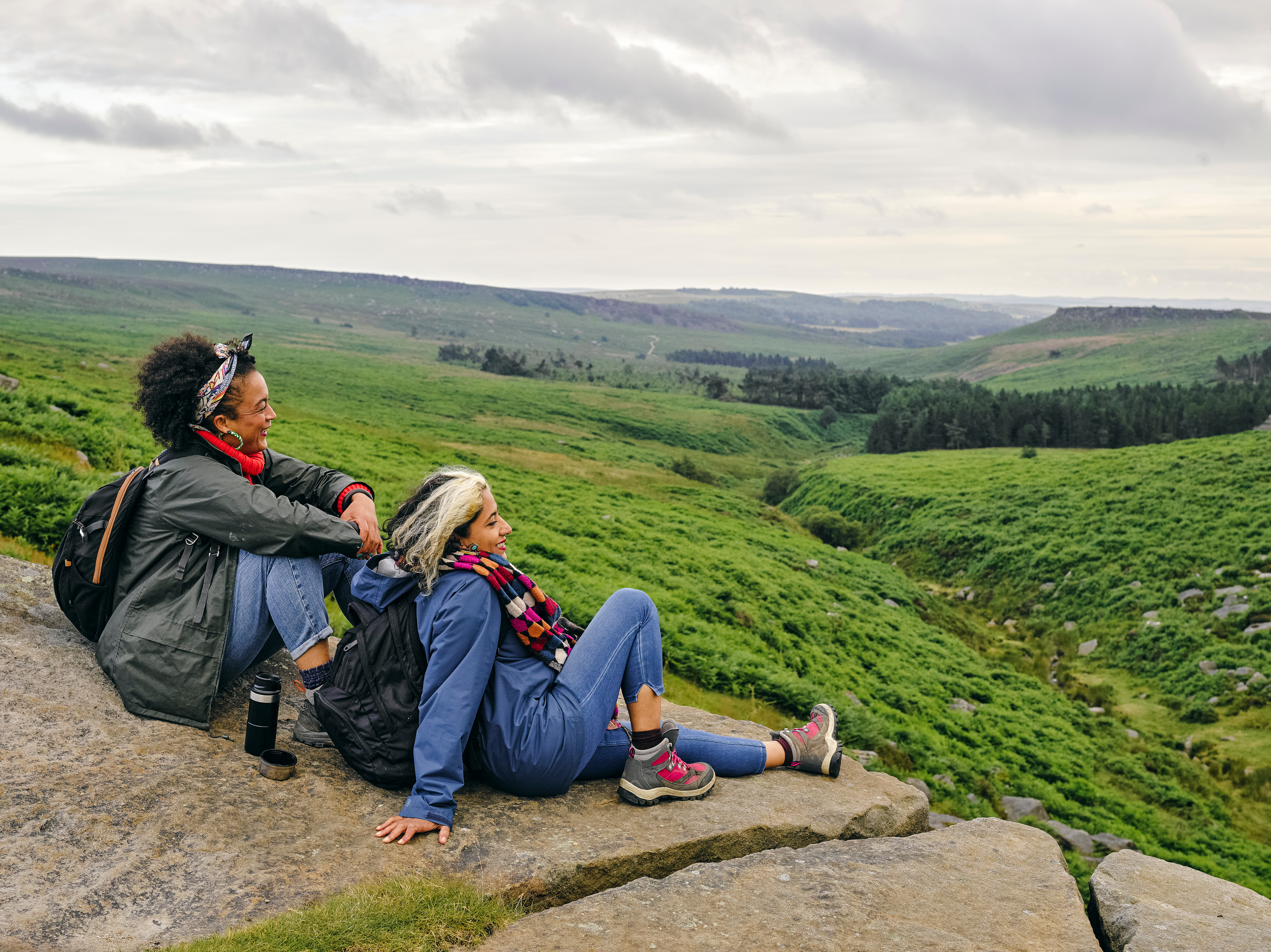 two women sit and look at a view on a hike