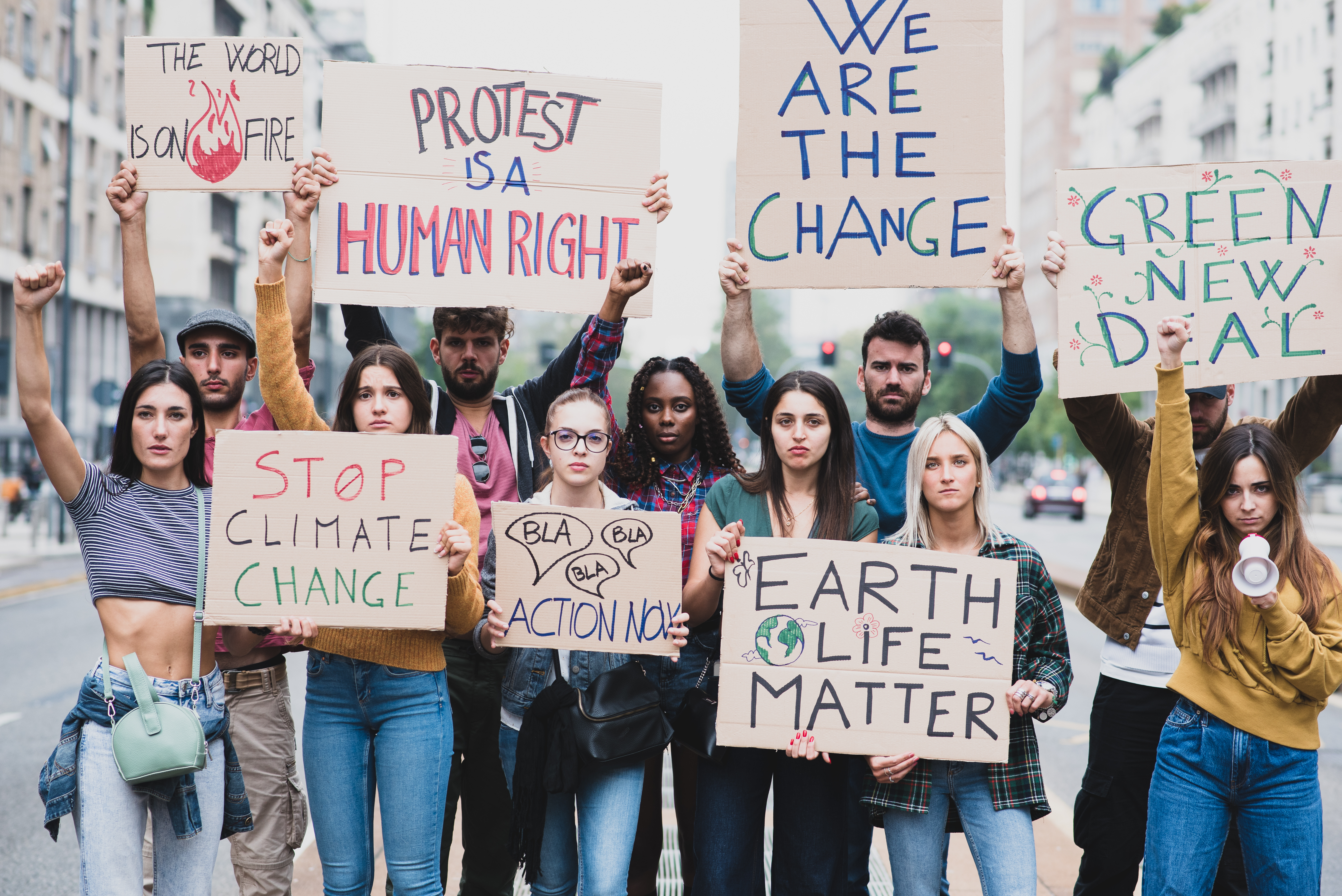 A group of young people stand in the street holding signs