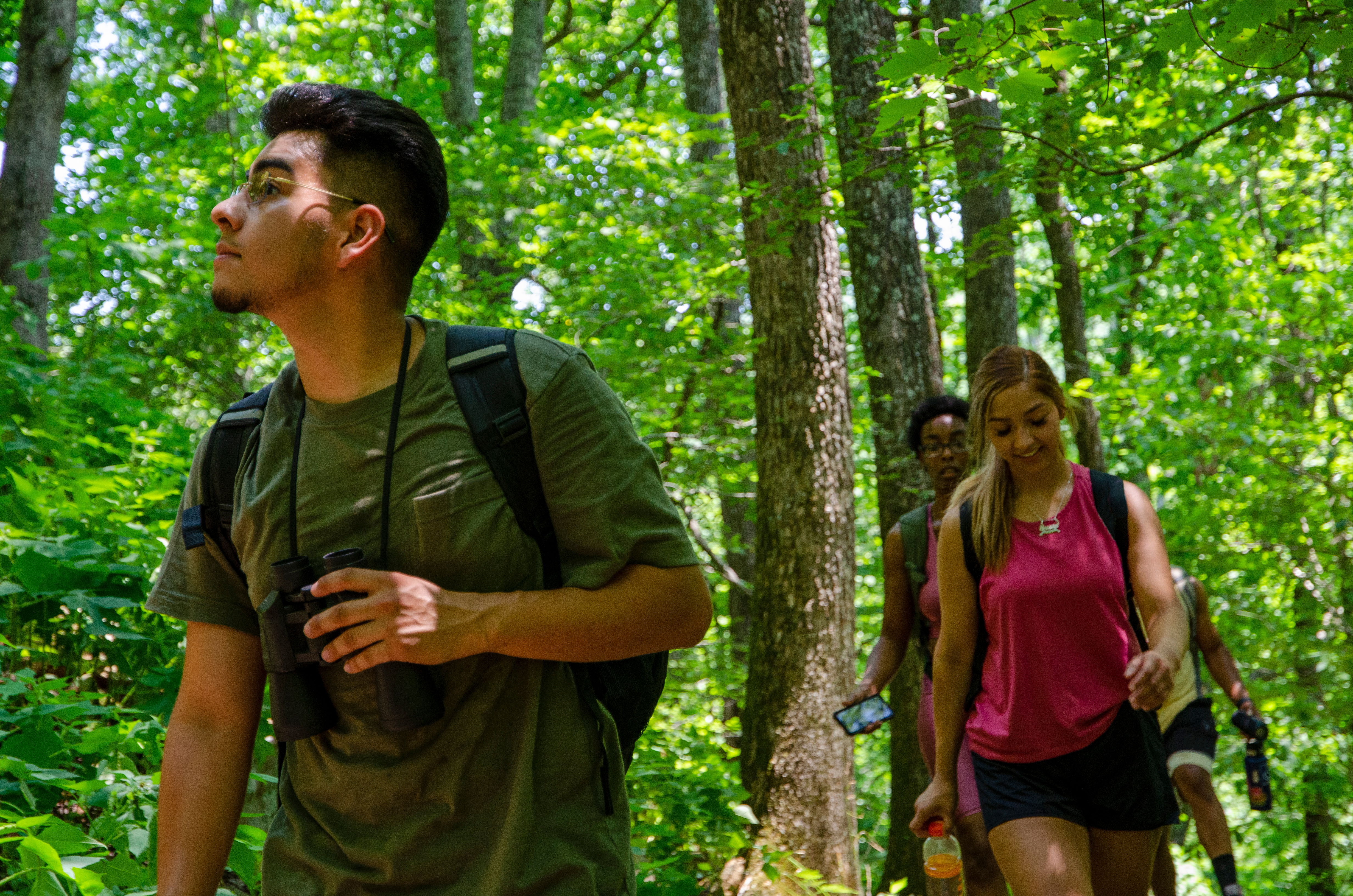 A group of young people walk down a trail surrounded by trees