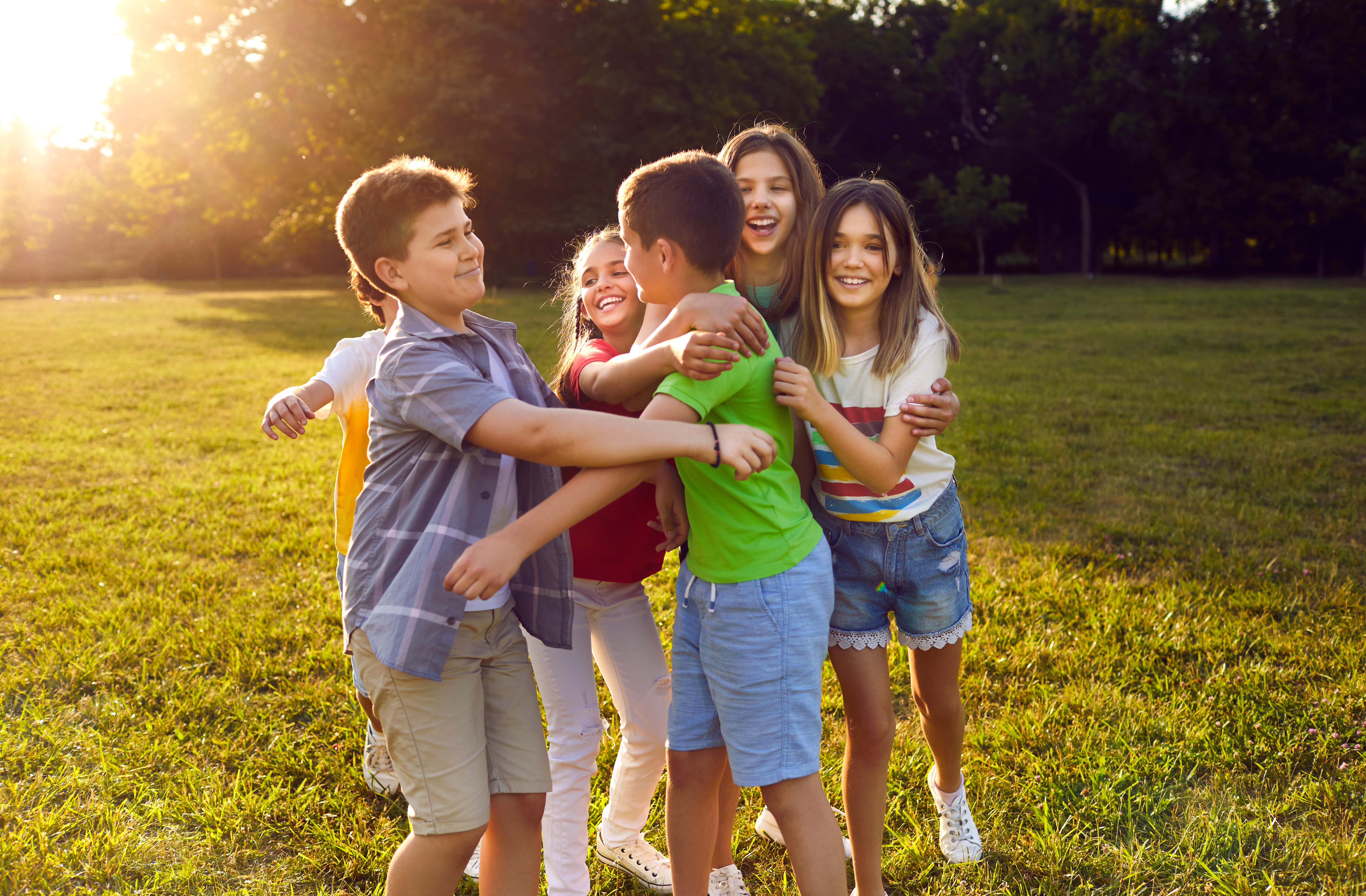 a group of kids hug in a field of grass